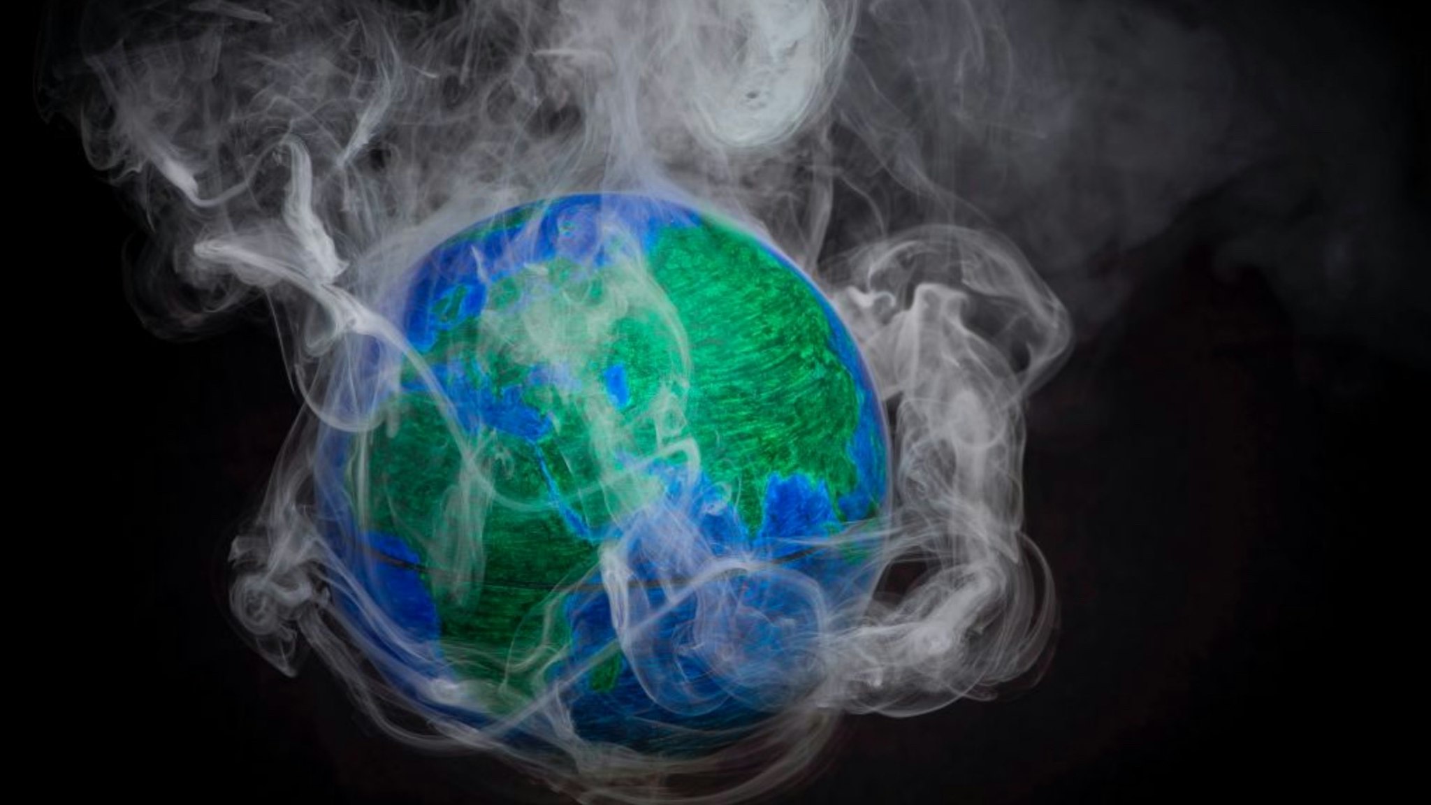 A picture taken on November 10, 2015 shows a small globe surrounded by smoke to illustrate global warming.