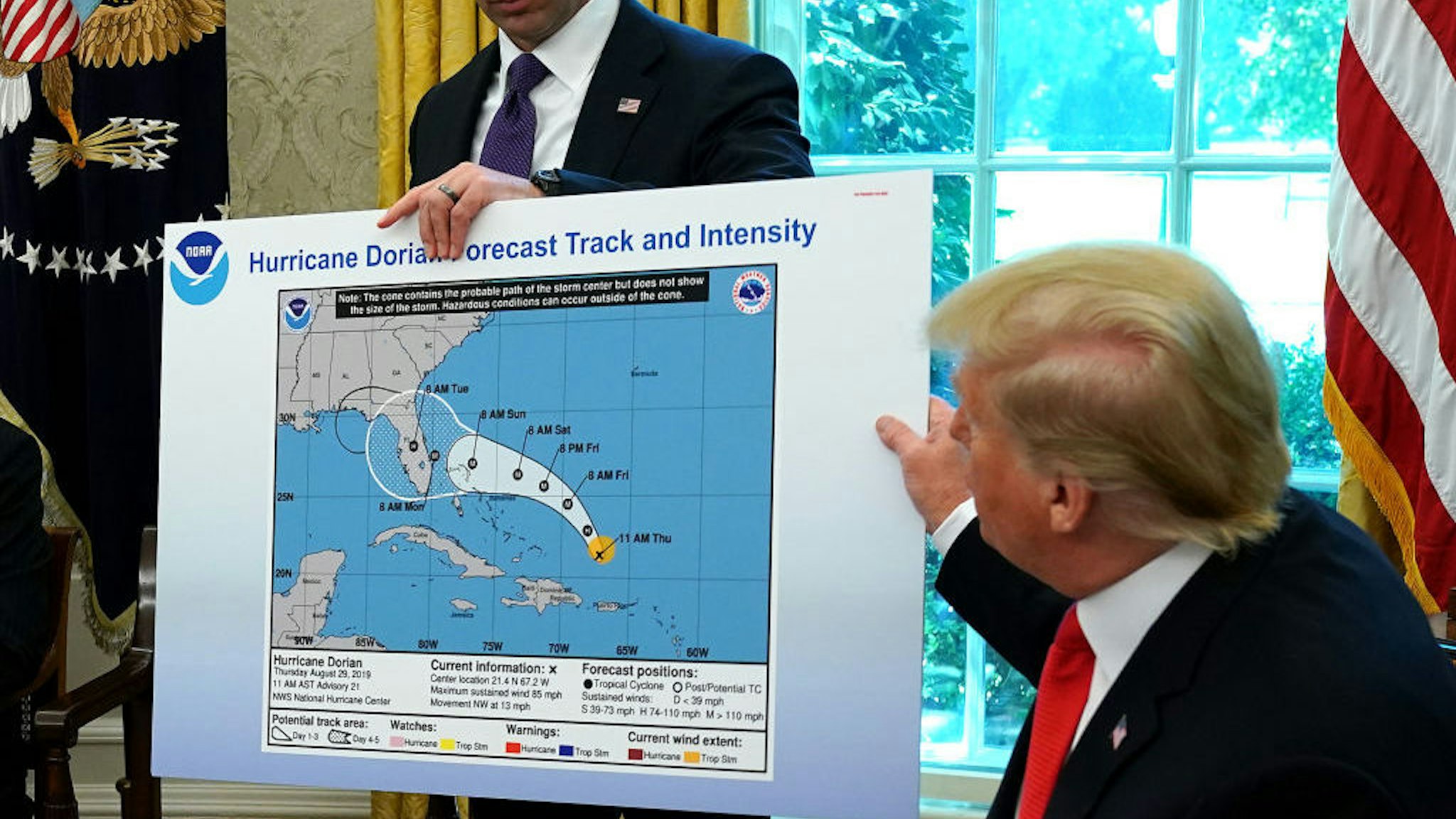 U.S. President Donald Trump (R) references a map held by acting Homeland Security Secretary Kevin McAleenan while talking to reporters following a briefing from officials about Hurricane Dorian in the Oval Office at the White House September 04, 2019.