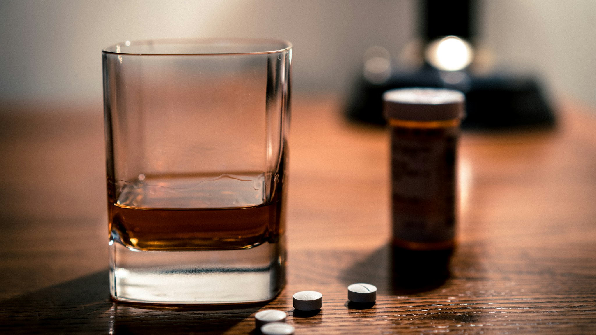 Opiate pills and alcohol epidemic -- close up of pills and glass of booze.