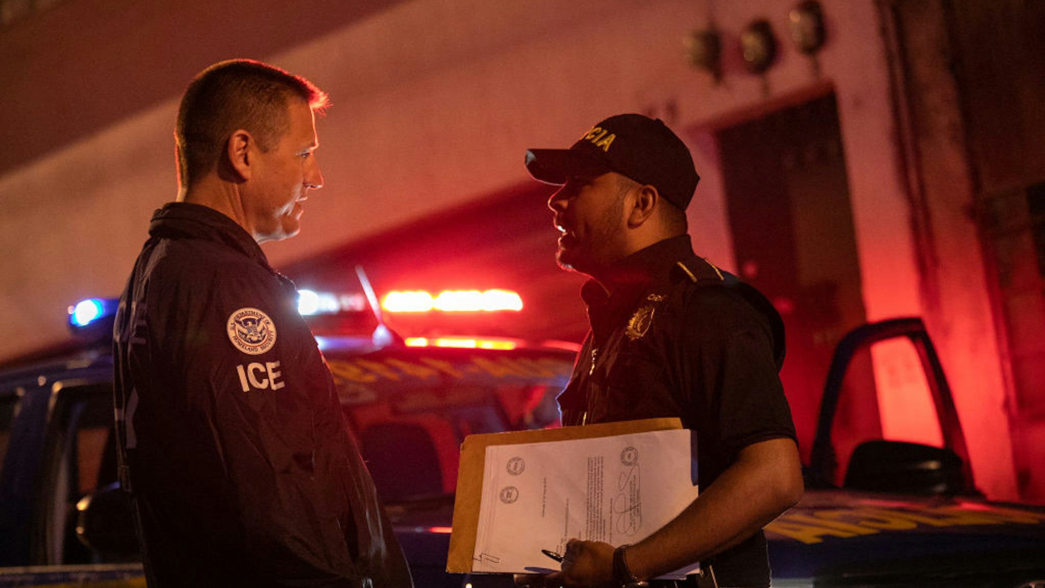 An ICE agent with U.S. Homeland Security Investigations (HSI), (L) and a Guatemalan policeman speak at the scene of a raid where a suspected human trafficker was taken into custody on May 29, 2019 in Guatemala City.