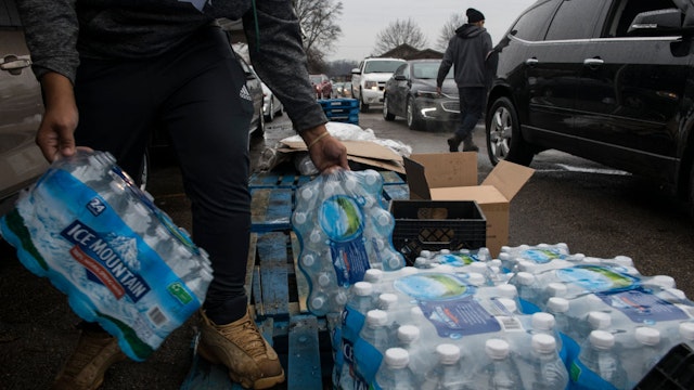 FLINT, MICHIGAN - DECEMBER 20: Workers load bottled water into vehicles waiting in line at a water distribution site at Greater Holy Temple in Flint, Mich., on Thursday, December 20, 2018.