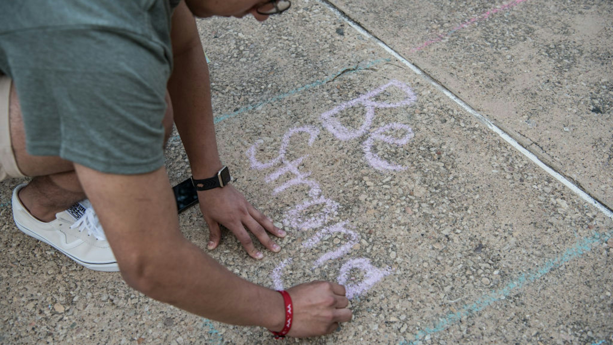 Juan Perez, 17, writes with chalk during a vigil at the University of Texas of the Permian Basin (UTPB) for the victims of a mass shooting, September 1, 2019 in Odessa, Texas.