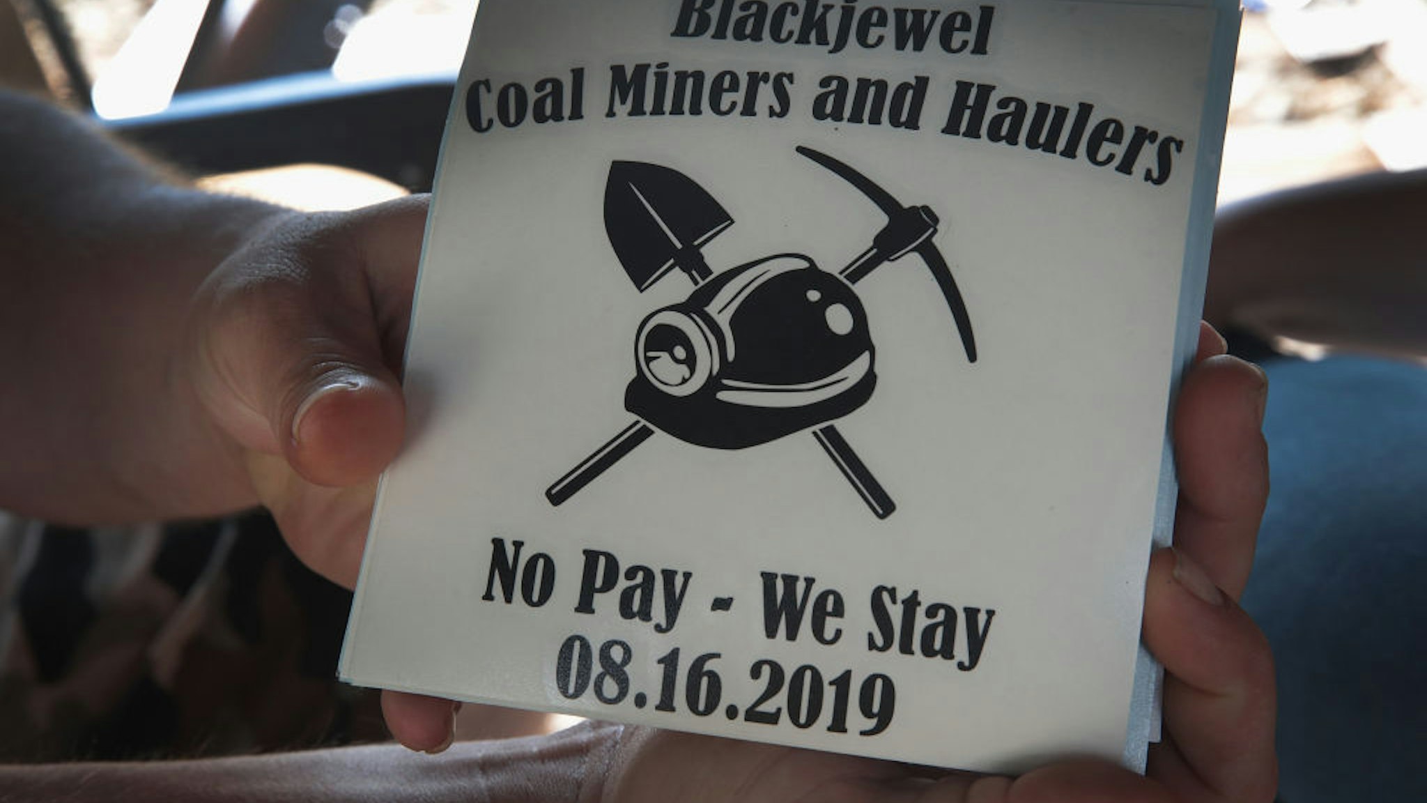 CUMBERLAND, KENTUCKY - AUGUST 24: Chris Rowe, an unemployed Blackjewel coal miner, shows off stickers that were made for the miners while he mans a blockade of the railroad tracks that lead to the mine where he once worked on August 24, 2019 in Cumberland, Kentucky. More than 300 miners in Harlan County unexpectedly found themselves unemployed when Blackjewel declared bankruptcy and shut down their mining operations.