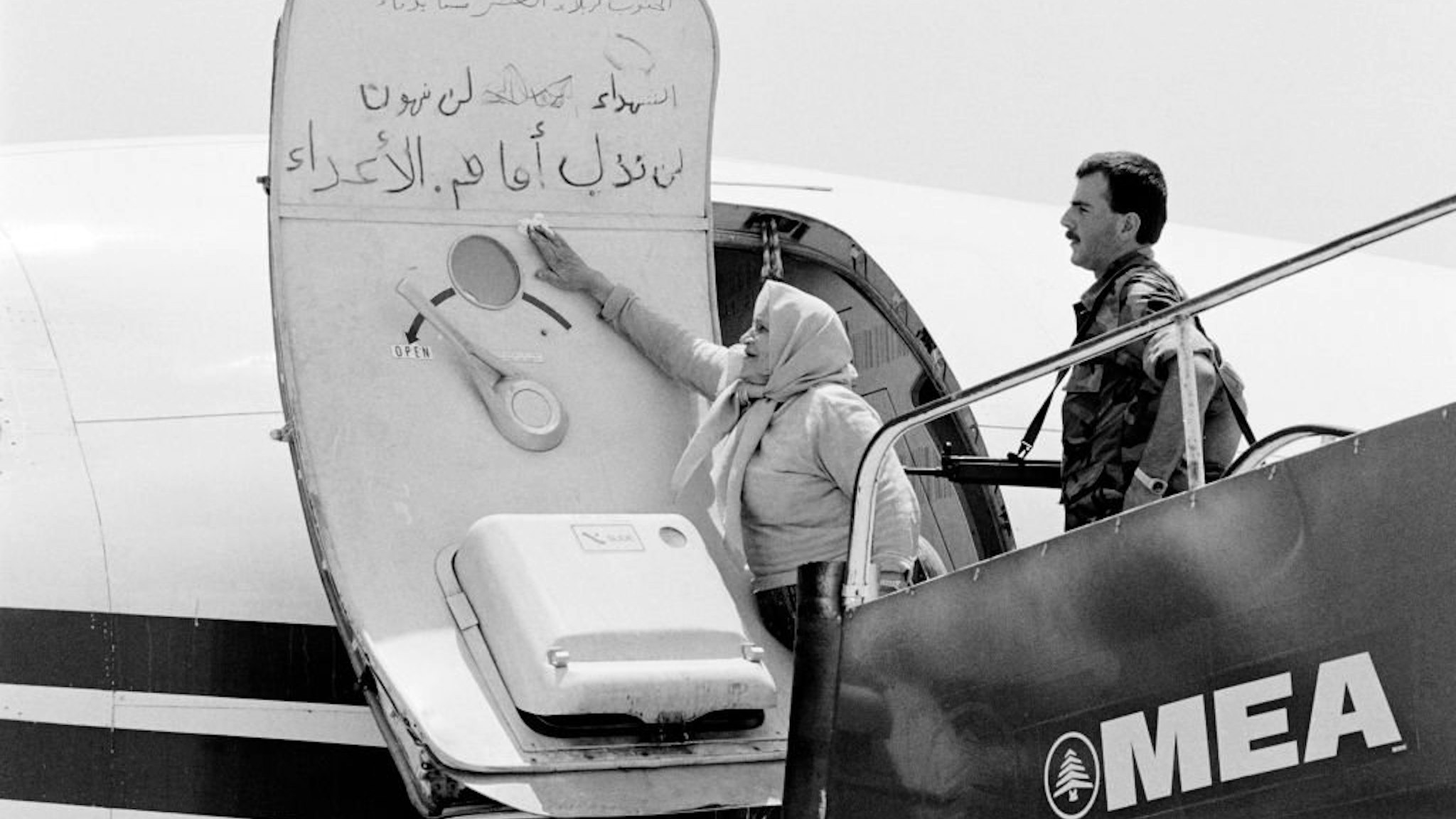 A Lebanese woman cleans the slogans which have been writting by the hijackers on the door of the TWA plane, on July 6, 1985 at Beirut airport.