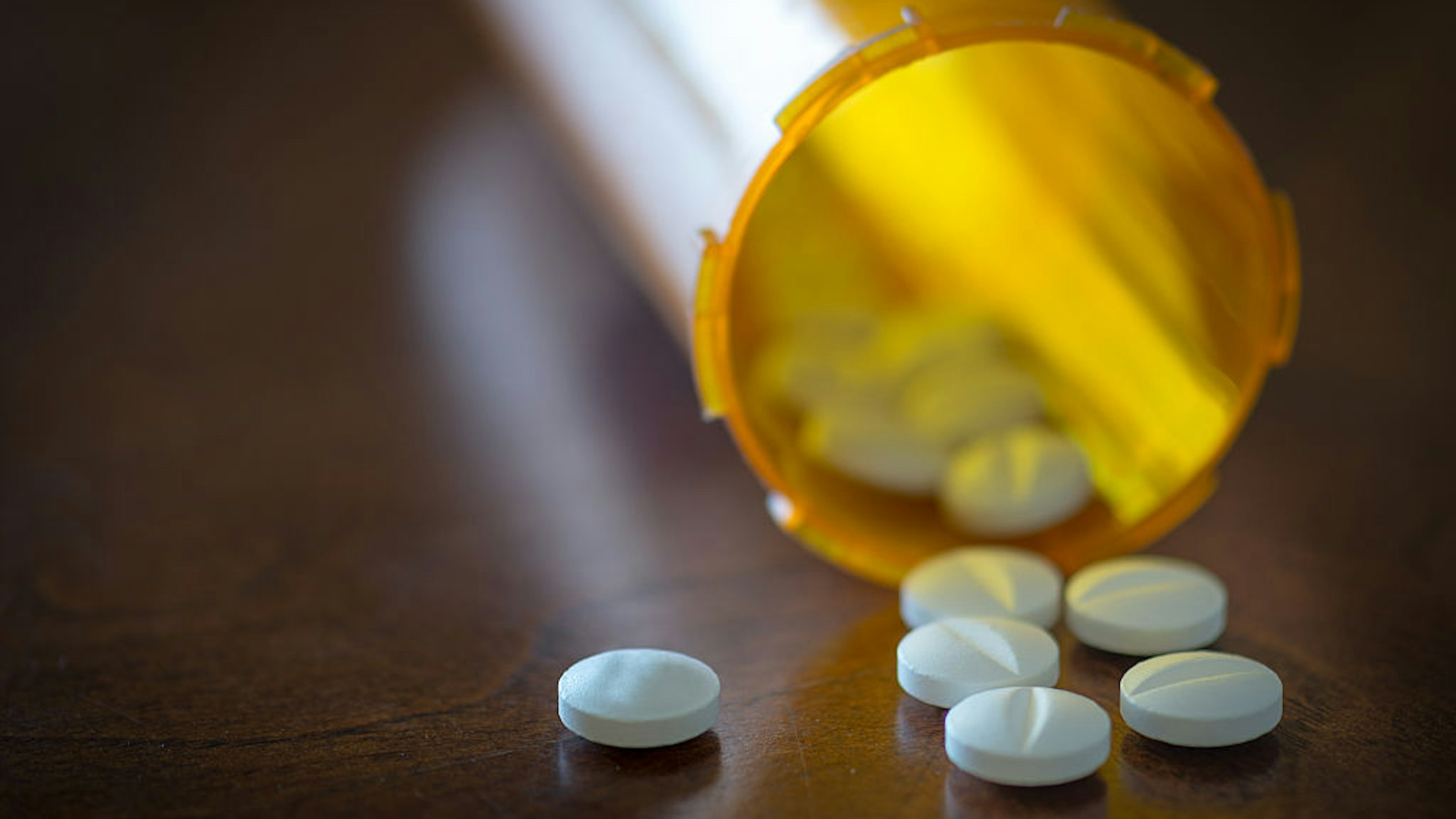 CANADA - 2016/01/21: Prescription pills in a yellow bottle over a wooden table with selective depth of field.