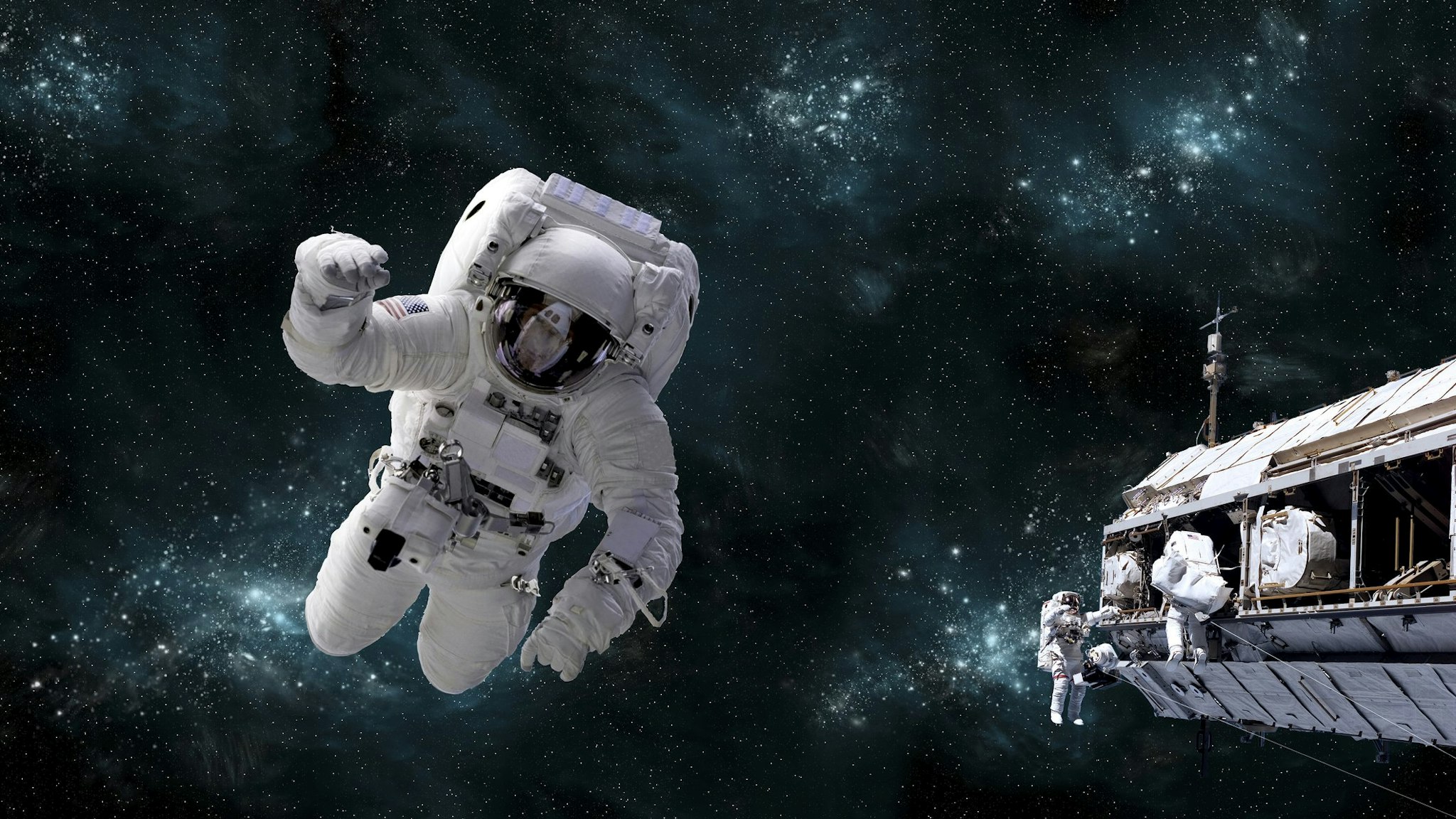 Artists concept of astronaut floating in outer space while his fellow astronauts work on the space station. A galactic scene serves as background.