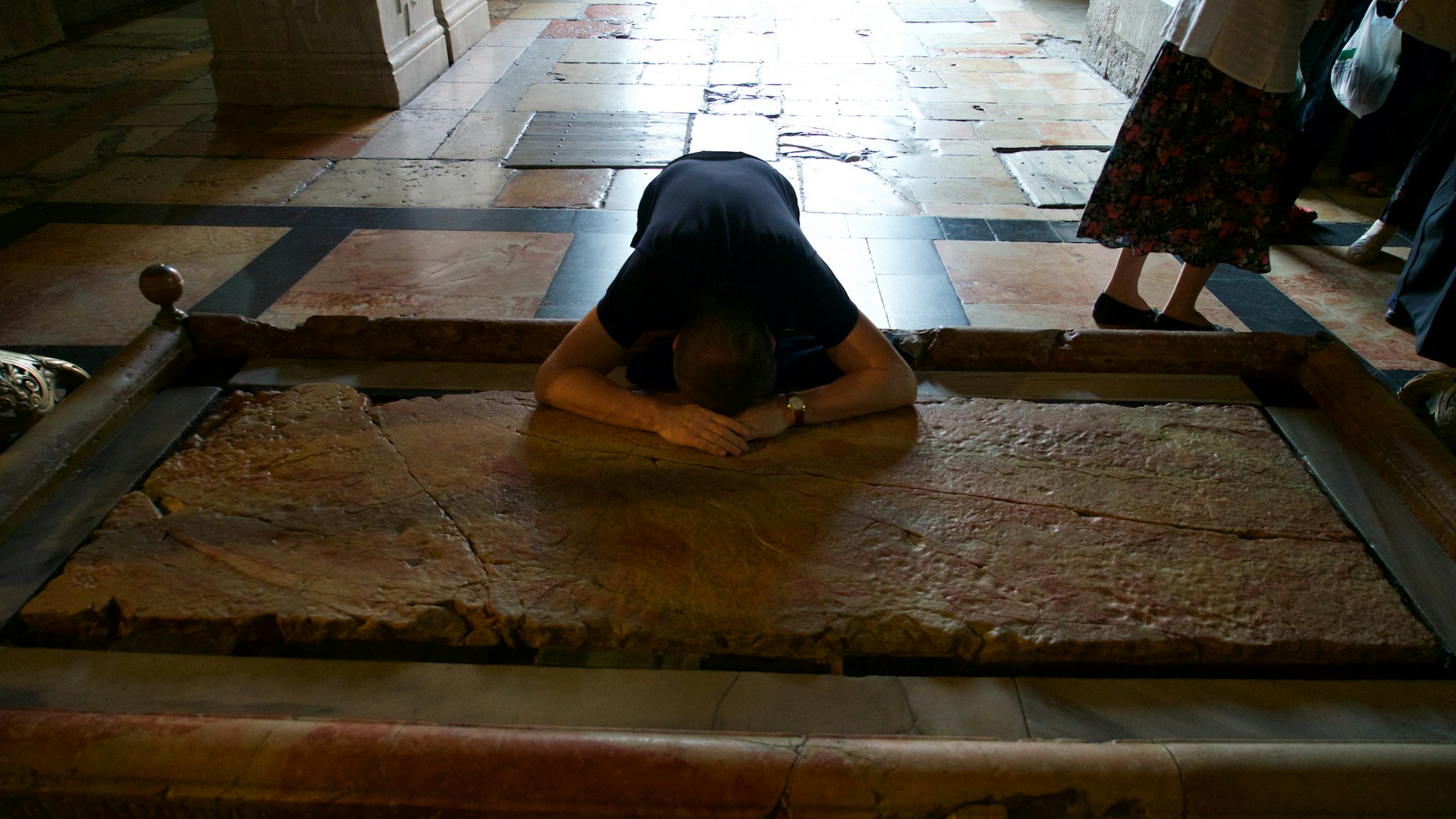 Stone of the Anointing (or Unction) in Church of the Holy Sepulchre, Pilgrim praying, Old City of Jerusalem (Unesco World Heritage List, 1981), Israel.