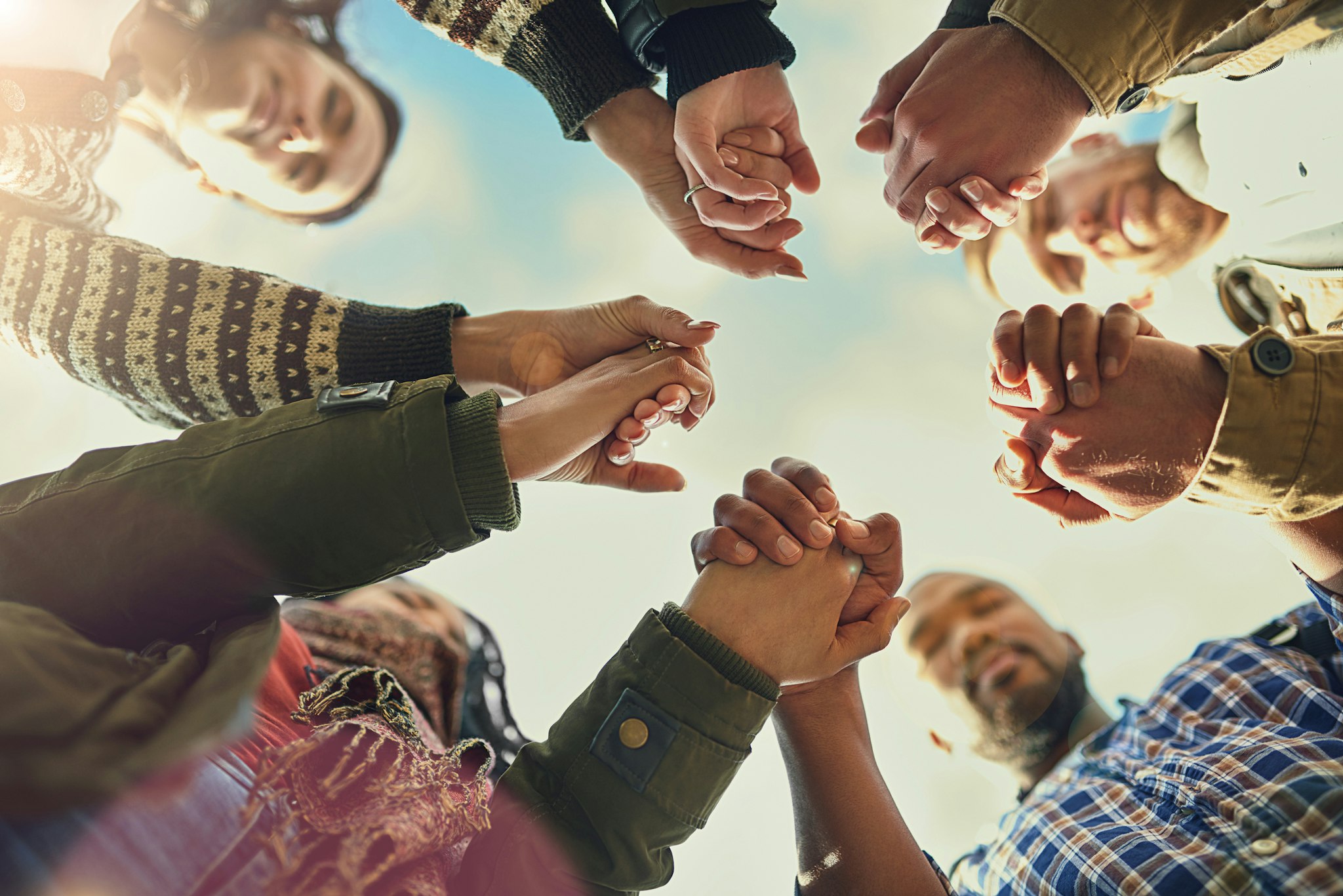 Shot of a group of friends putting their hands together in prayer.