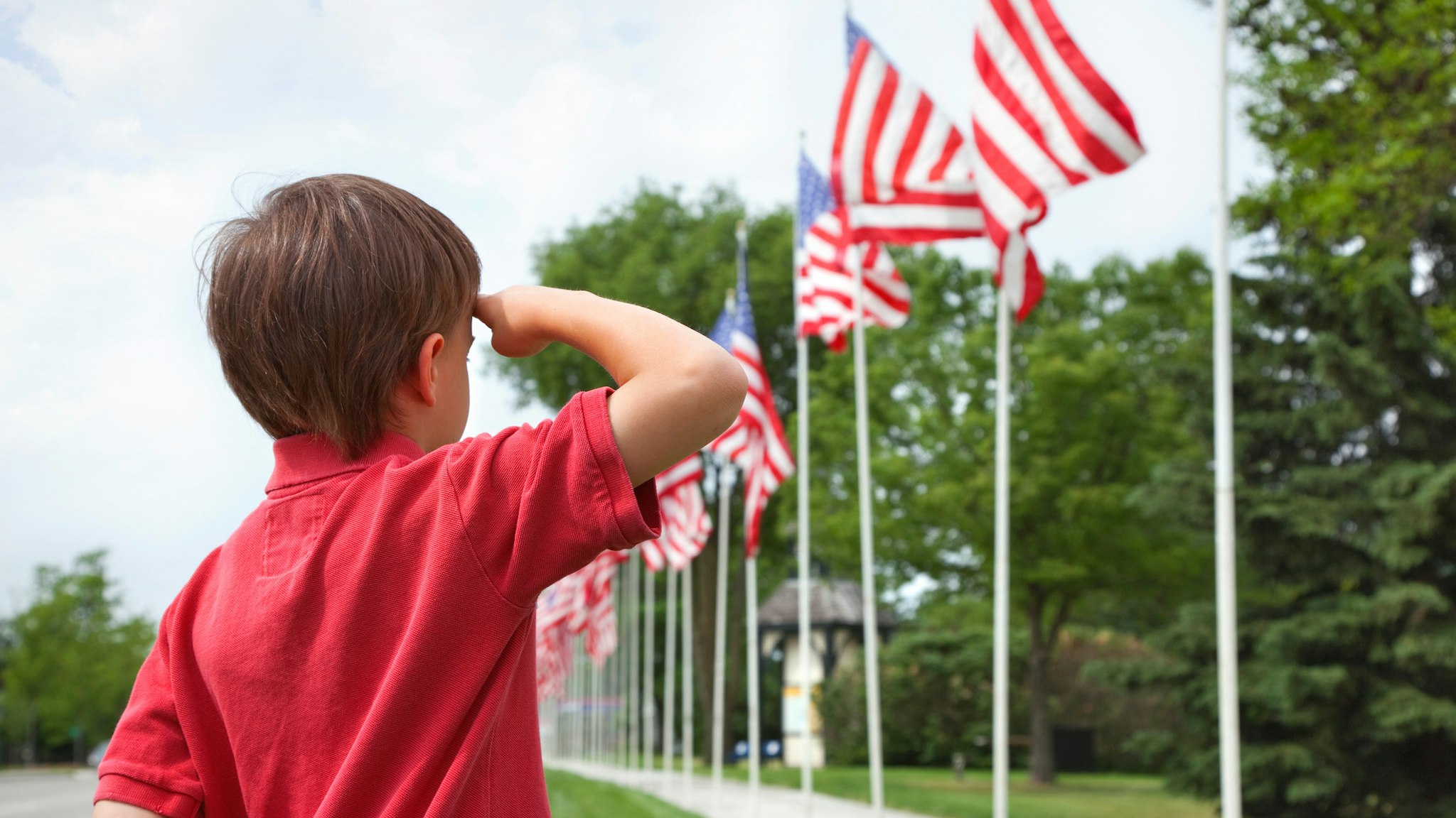 A young boy salutes the flags of a Memorial Day display along a small town street