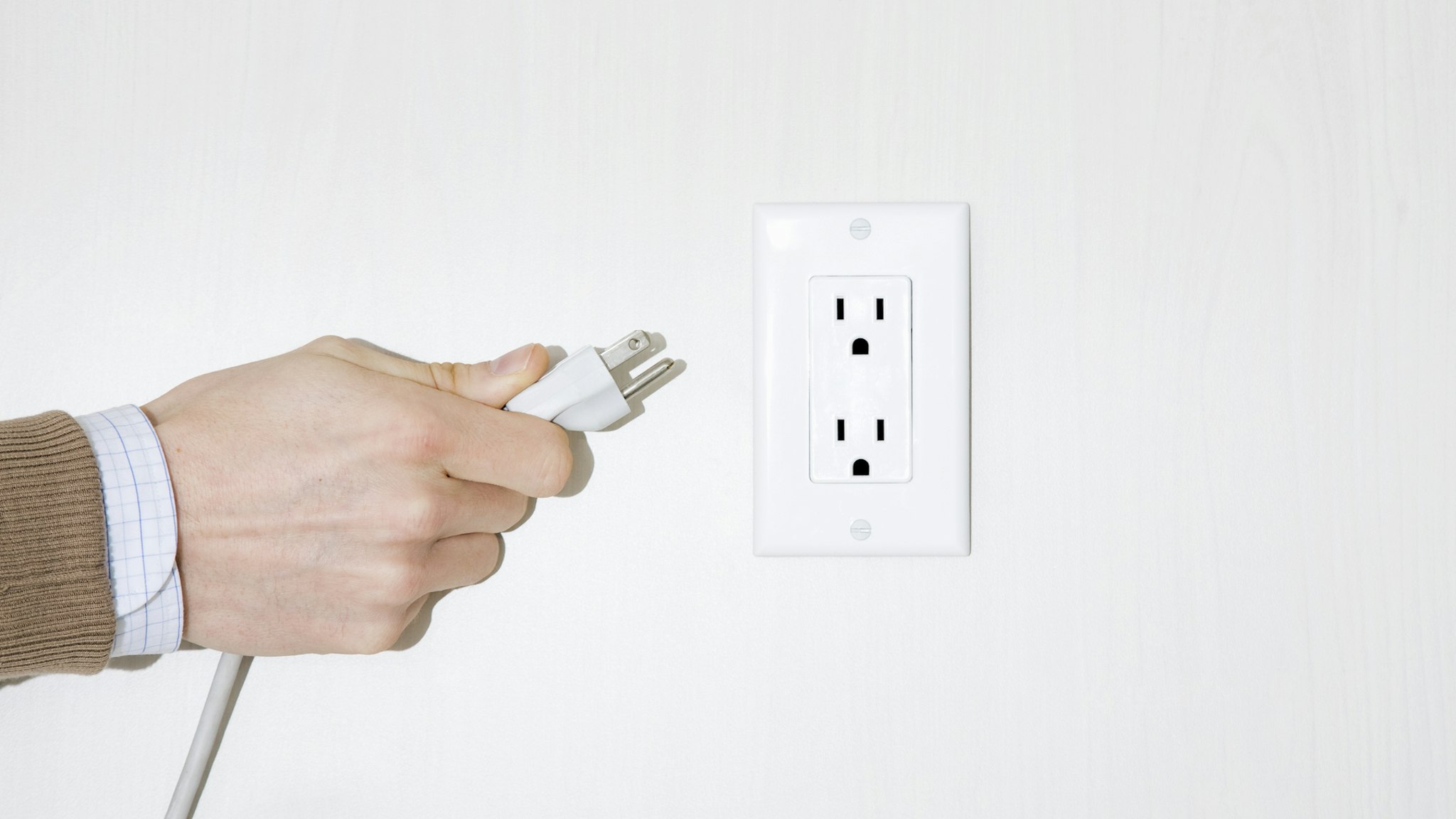 Man pulling electrical plug out of wall, close-up