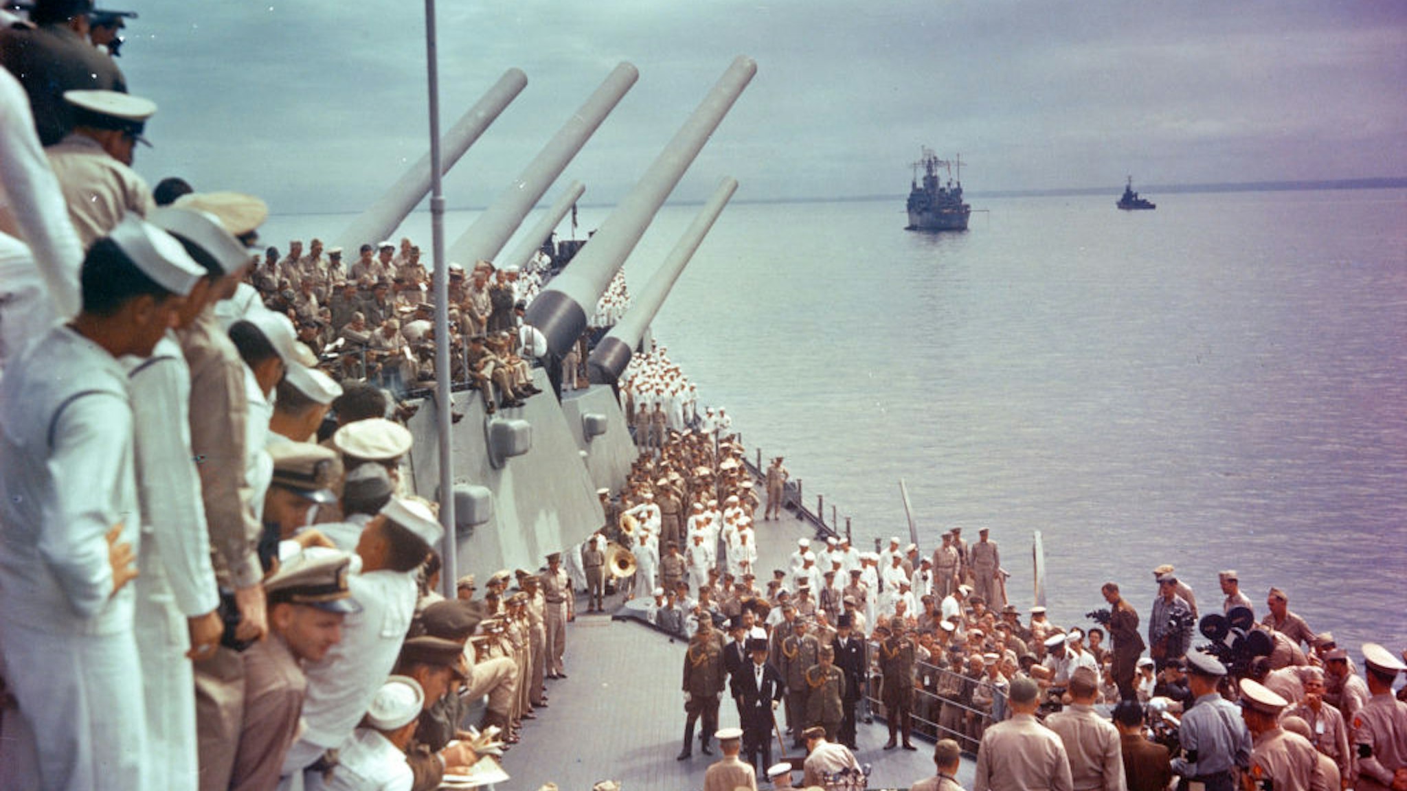 General view of US sailors as they watch the signing of the Japanese Instrument of Surrender (which ended World War II) on the deck of the USS Missouri, anchored in Tokyo Bay, Japan, September 2, 1945. Dutch Lieutenant-Admiral Conrad Helfrich (1886 - 1962) (seated at table, center bottom) is signing as, among those also pictured, US General Douglas MacArthur (1880 - 1964) (standing to Helfrich's right) and the members of the Japanese delegation watch. They are, front row from left Japanese Minister of Foreign Affairs Mamoru Shigemitsu (1887 - 1957) (with cane) and Chief of the General Staff General Yoshijiro Umezu (1882 - 1949); second row, Major General Yatsuji Nagai (1901 - 1970), Foreign Minister Katsuo Okazaki (1897 - 1965), Rear Admiral Tadatoshi Tomioka (1897 - 1970), Foreign Minister Toshikazu Kase (1903 - 2004), and Lieutenant General Suichi Miyakazi (1895 - 1969); third row, Rear Admiral Ichiro Yokoyama (1900 - 1993), Foreign Minister Saburo Ohta, Captain Katsuo Shiba (1901 - 1970), and Colonel Kaziyi Sugita (1904 - 1993).