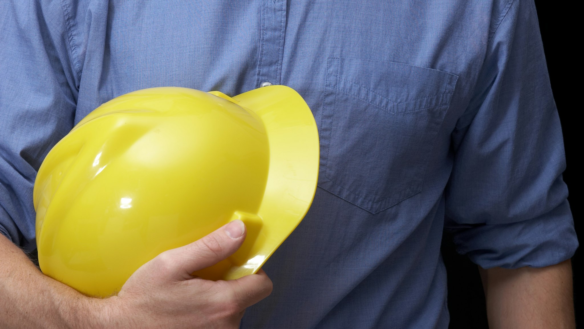 Torso of a man with yellow hardhat and blue work shirt