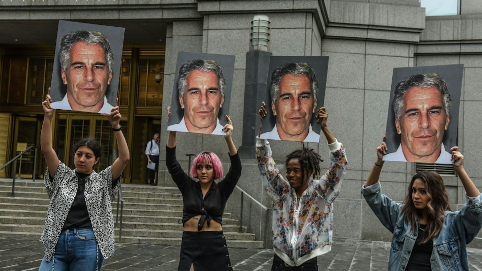 A protest group called "Hot Mess" hold up signs of Jeffrey Epstein in front of the Federal courthouse on July 8, 2019 in New York City.
