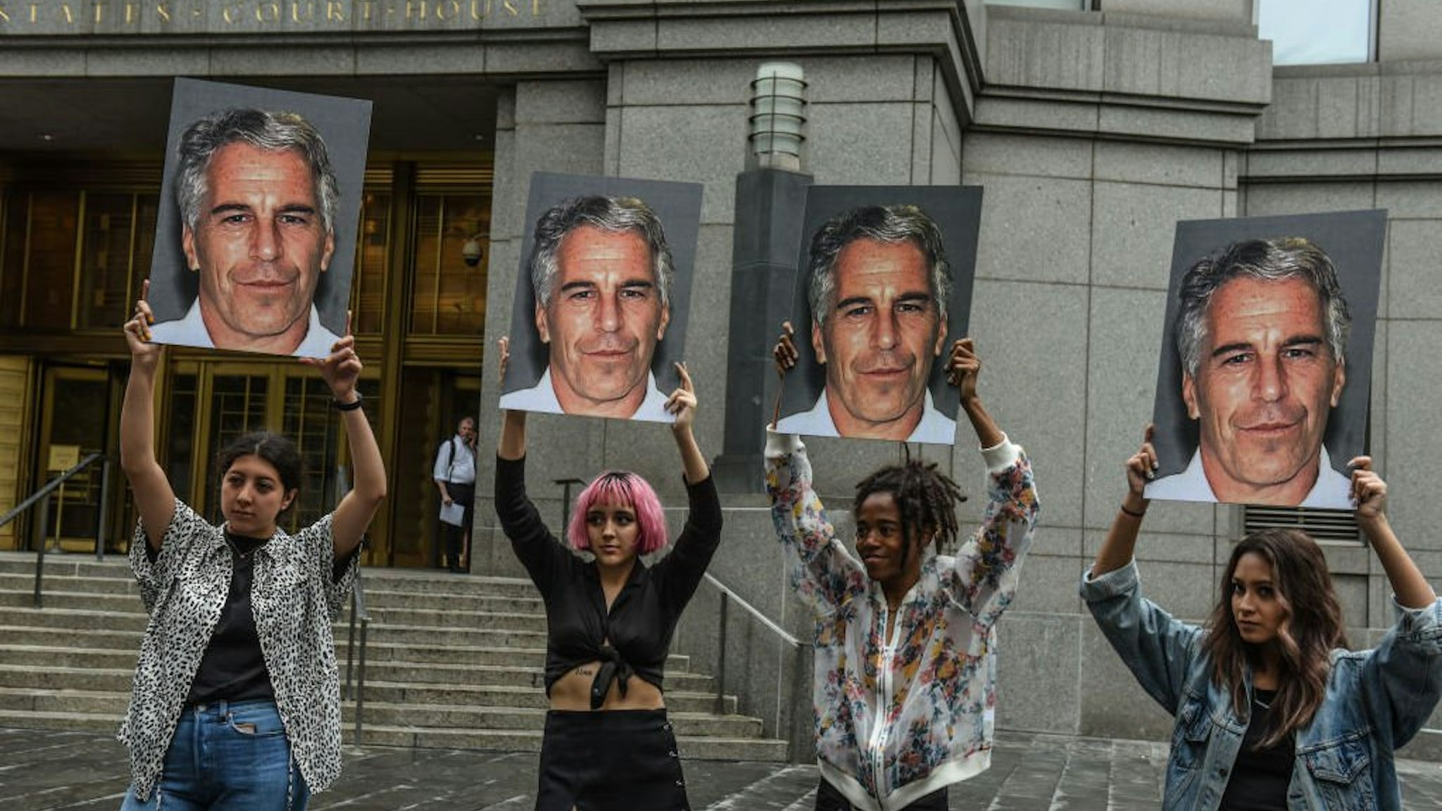 A protest group called "Hot Mess" hold up signs of Jeffrey Epstein in front of the Federal courthouse on July 8, 2019 in New York City.