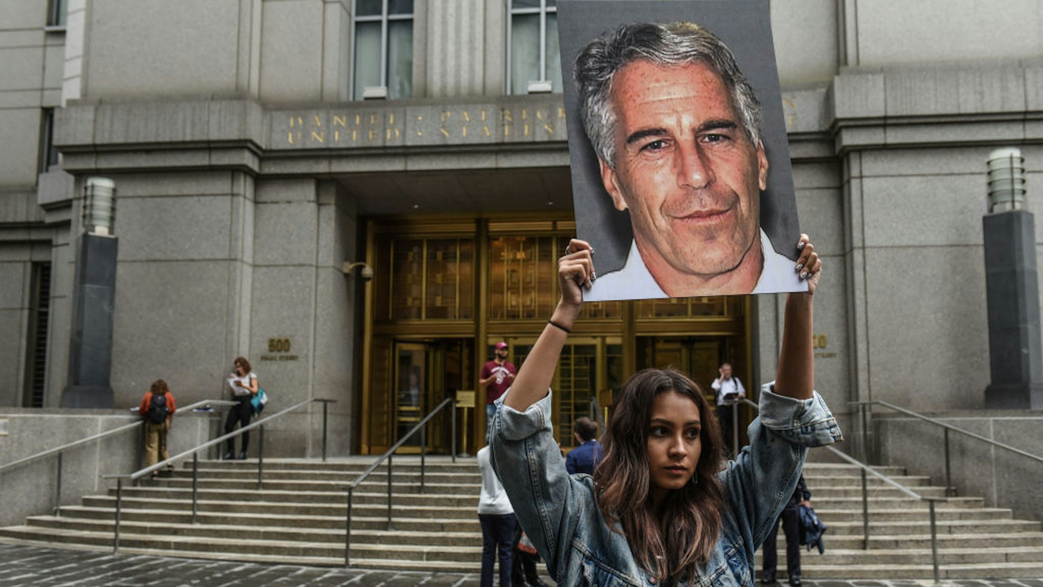 A protest group called "Hot Mess" hold up signs of Jeffrey Epstein in front of the federal courthouse on July 8, 2019 in New York City.