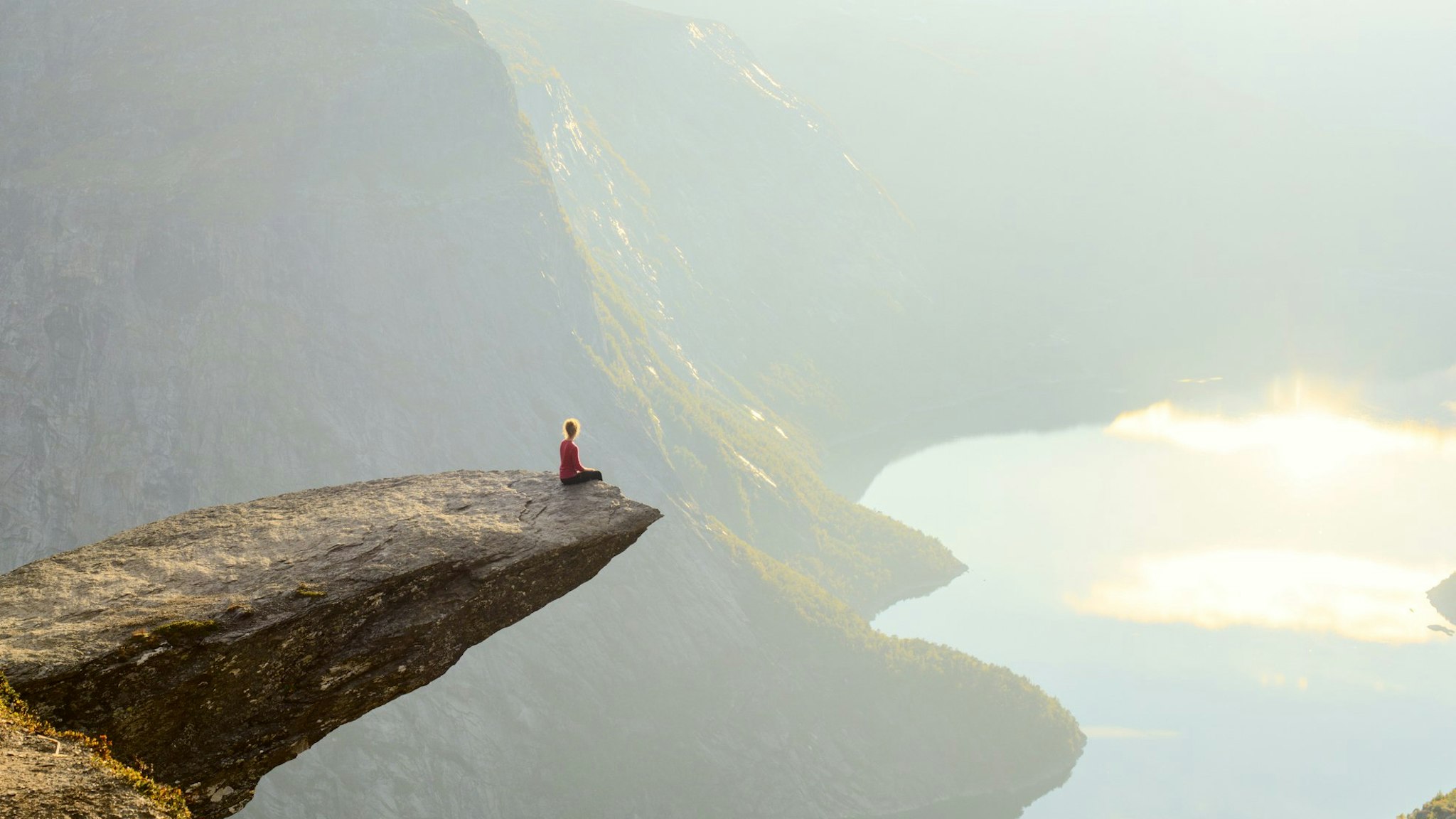 Woman sitting on Trolltunga at Odda, Hordaland county, Norway.