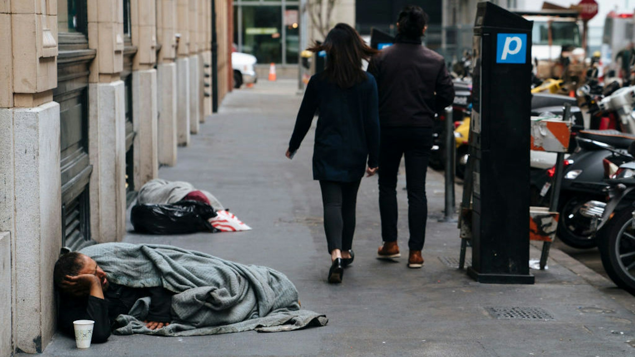 SAN FRANCISCO, CA - AUGUST 23: People walk by homeless people sleeping n San Francisco, California, on August 23, 2018.