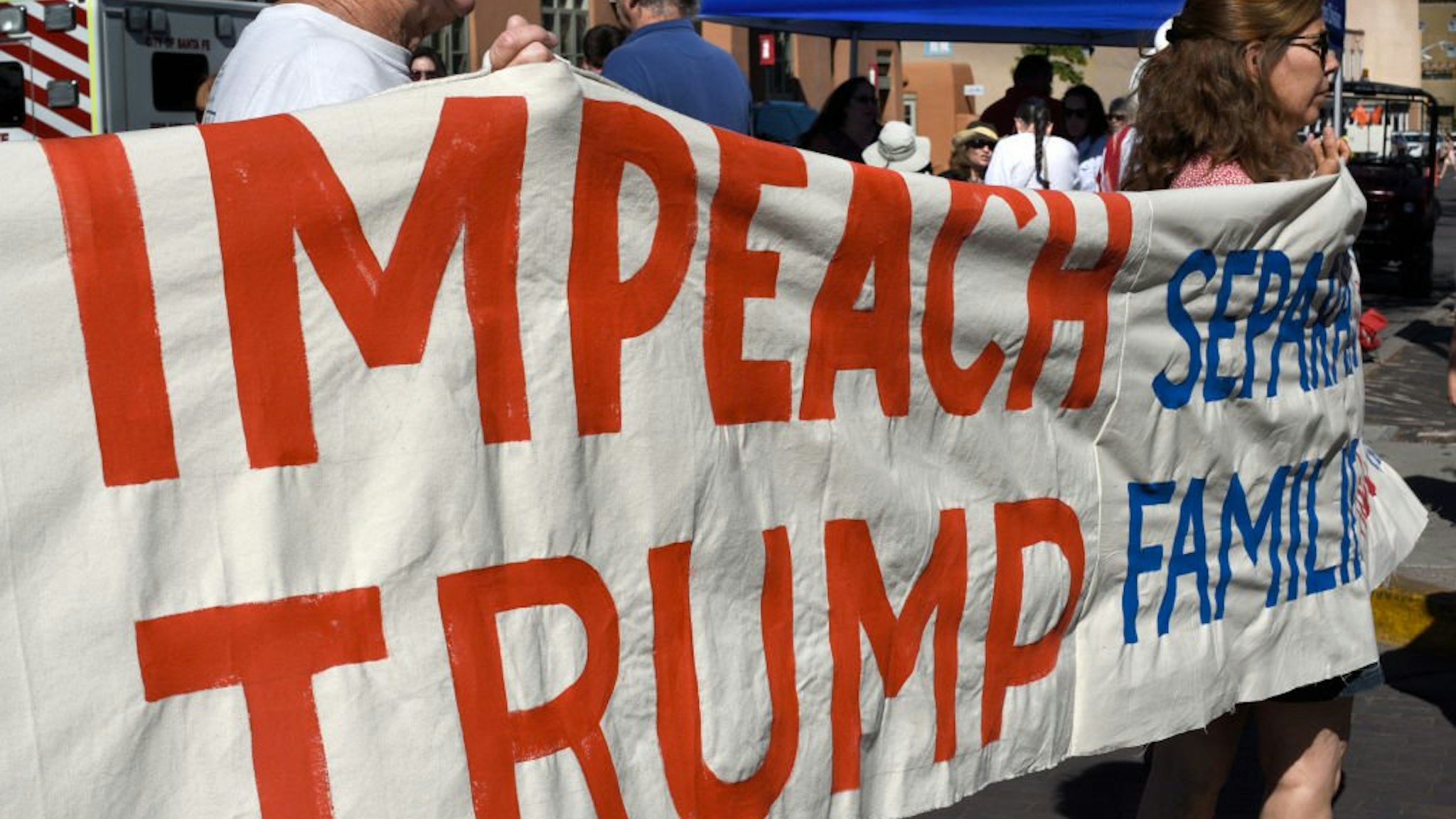Demonstrators carry a banner supporting the impeachment of Trump at a Fourth of July event in Santa Fe, New Mexico