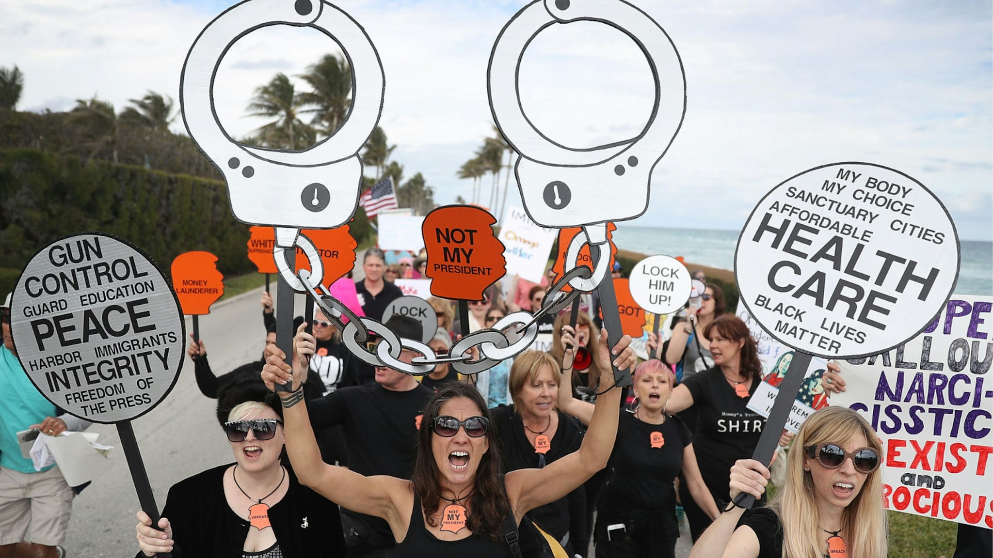 Alessandra Mondolfi (C) and other people protest against President Donald Trump on the one year anniversary of his inauguration on January 20, 2018 in Palm Beach, Florida.