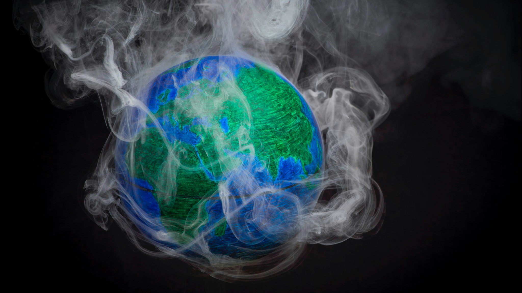 A picture taken on November 10, 2015 shows a small globe surrounded by smoke to illustrate global warming. France will be hosting and presiding the 21st Session of the Conference of the Parties to the United Nations Framework Convention on Climate Change (COP21/CMP11), also known as Paris 2015 from November 30 to December 11.