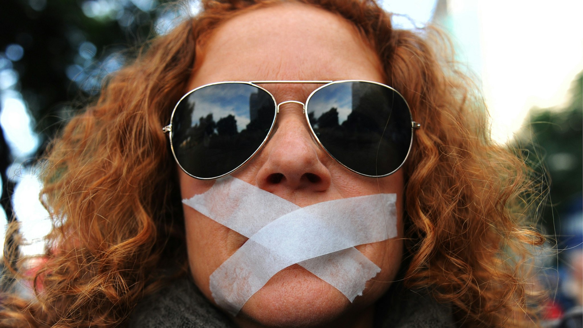 A woman wears tape over her mouth during a demonstration called by Nosomosdelito, a regrouping of some 40 collectives in Sevilla, against Spain's proposed new public security law, which introduces hefty fines for unauthorised protests and allows for the summary expulsion of migrants that try to enter the country illegally, has sparked fierce opposition from human rights activists, in Sevilla on December 27, 2014.