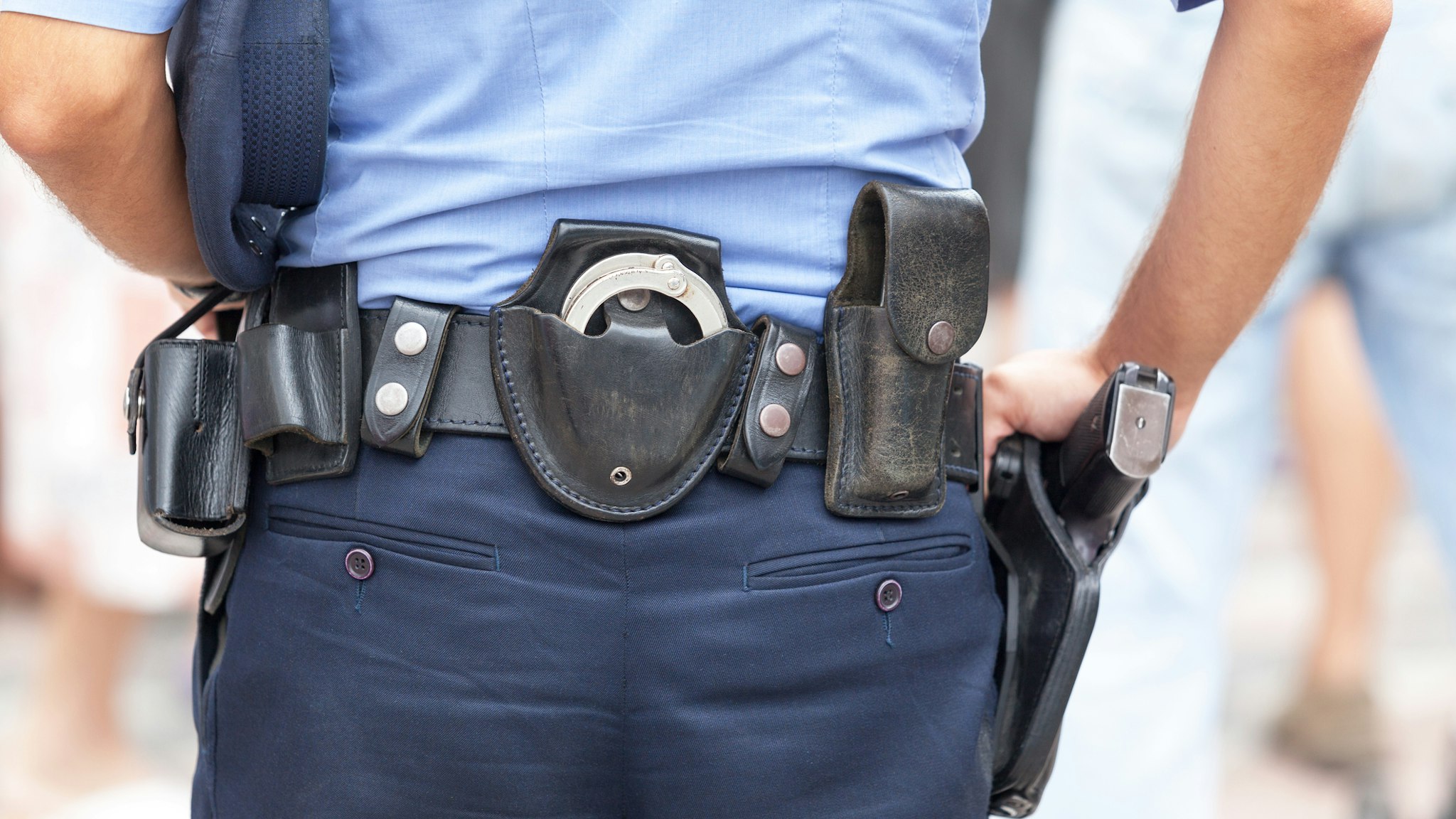 Midsection Rear View Of Police Man With Belt With Handcuffs And Gun - stock photo