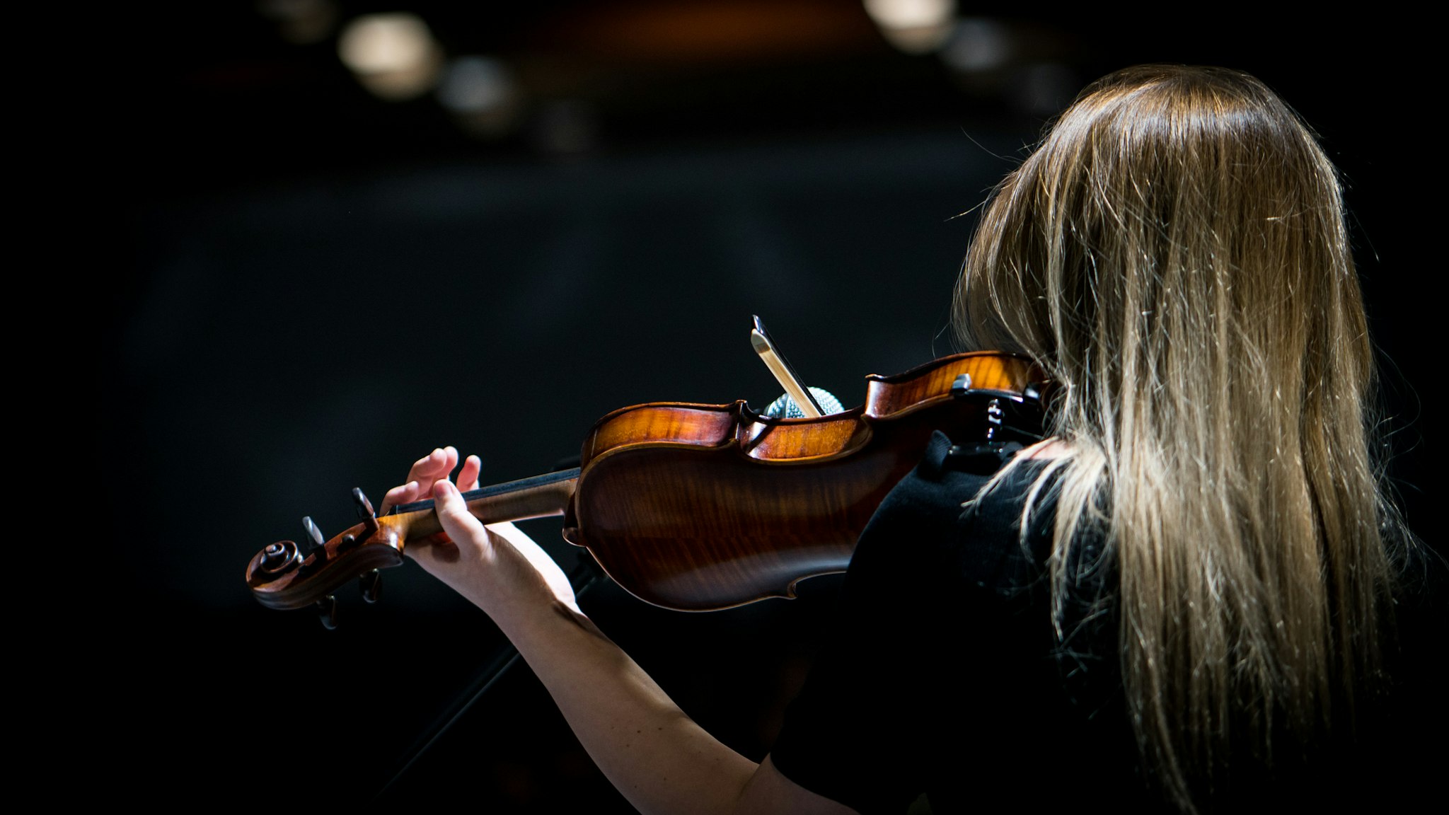Beautiful girl playing the violin in concert hall