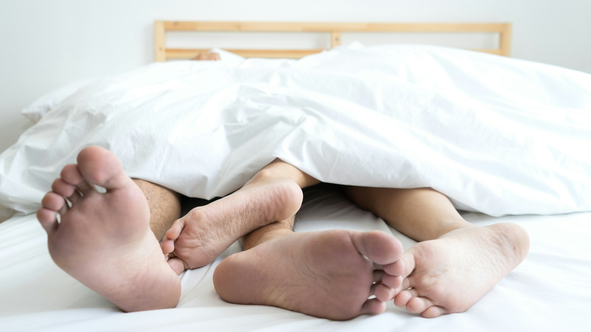 Low Section Of Couple Sleeping On Bed At Home - stock photo