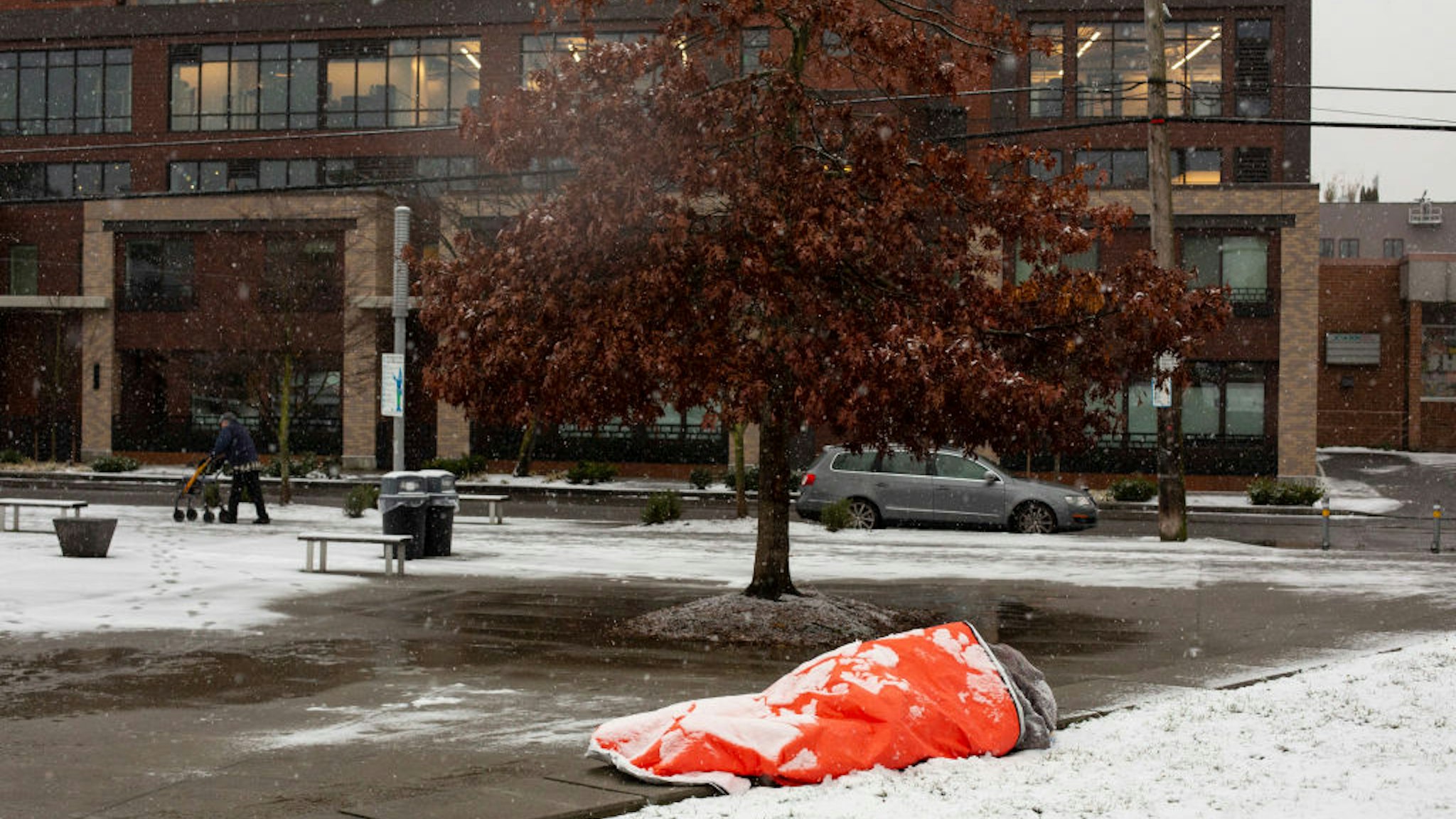 A homeless man, who said he was aware of the forecast for extreme weather, rests in a park while covered with snow on February 8, 2019 in Seattle, Washington.