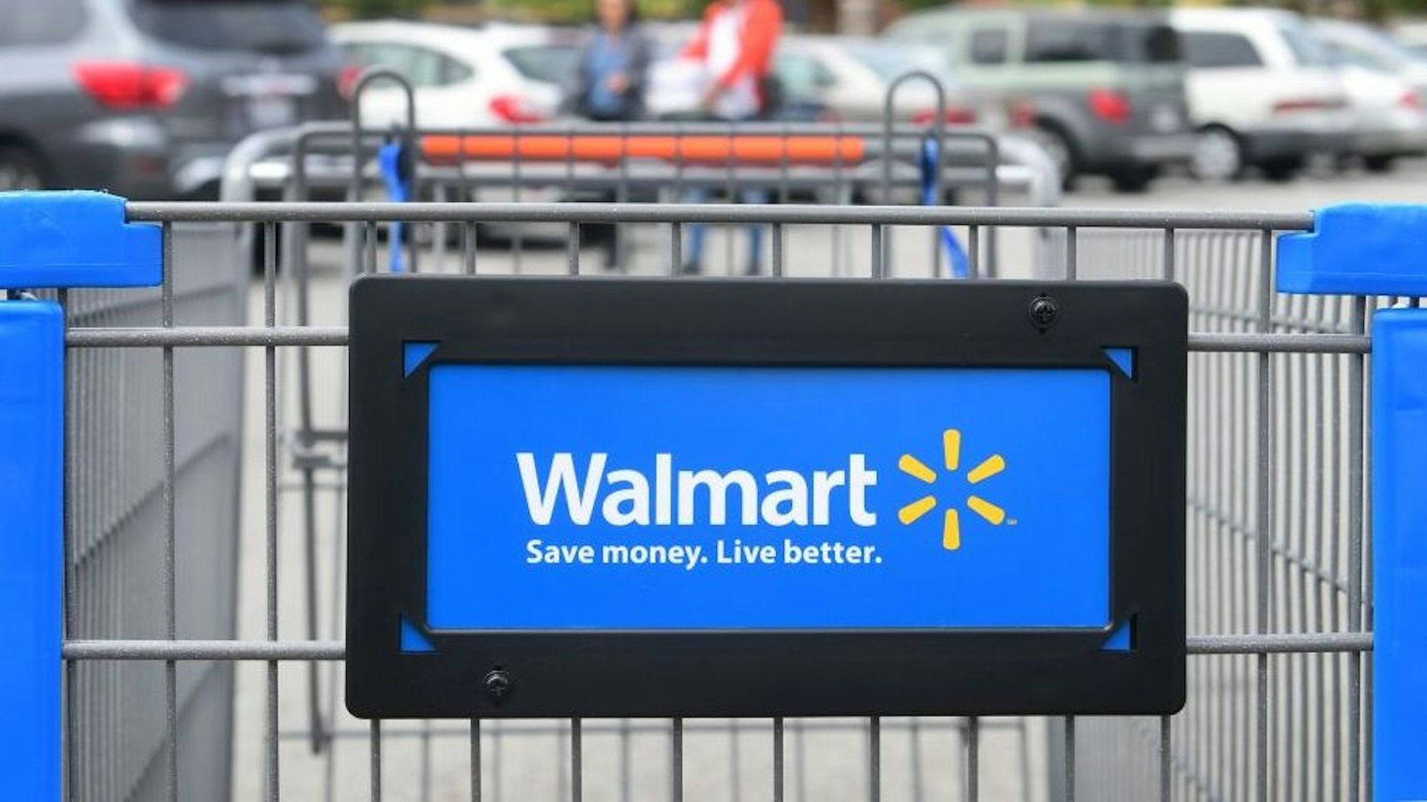 Shoppers carry their goods past a shopping cart in the parking lot of a Walmart Supercenter in Rosemead, California on May 23, 2019. - Walmart has said it will raise prices as a result of the Trump administration's tariffs on Chinese-made goods as the trade war is about to take a bite into the retail sector affecting consumers shopping at stores like Walmart, Target and Macy's.