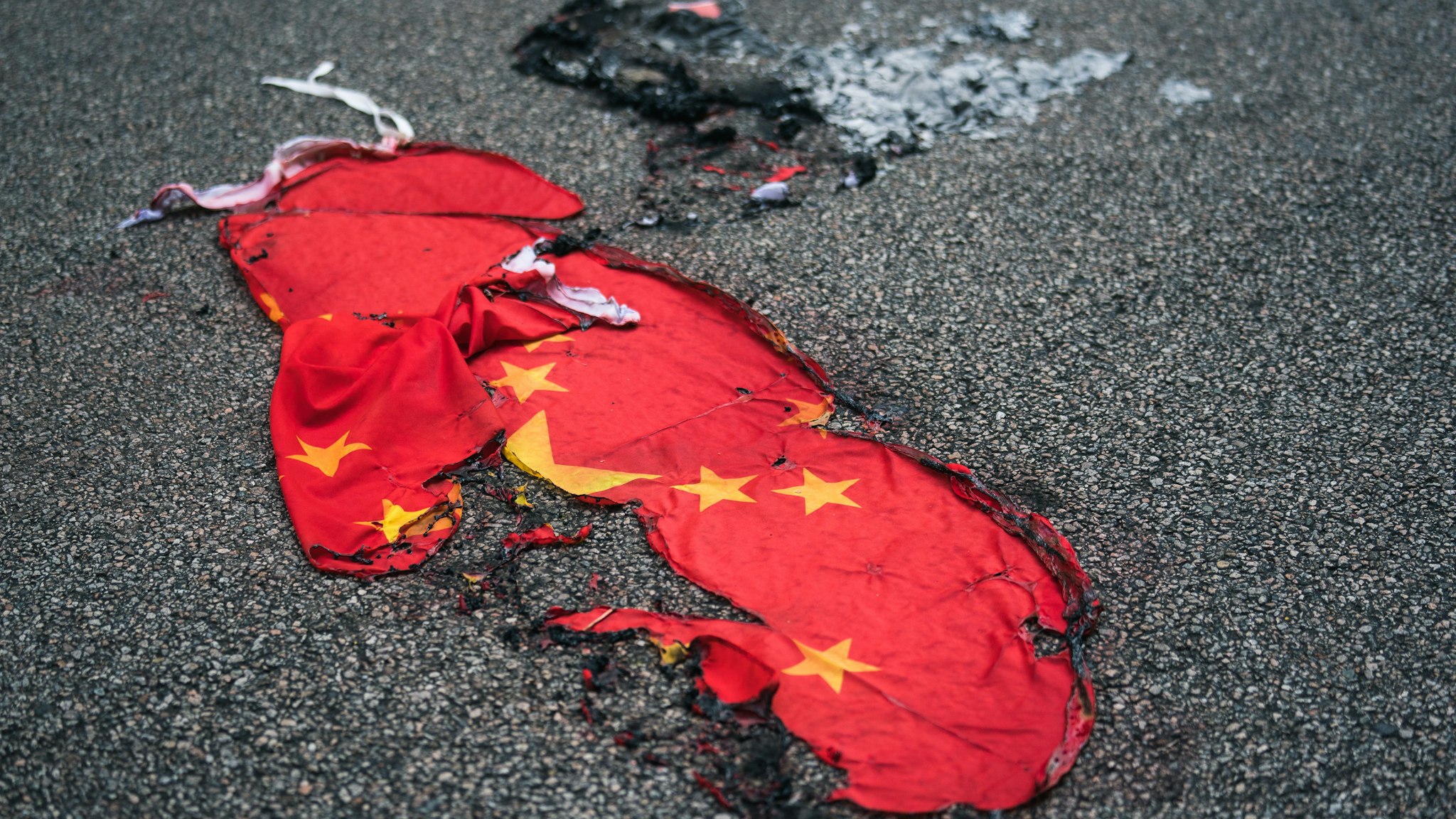 A Chinese national flag burnt on a street on October 01, 2019 in Hong Kong, China. Pro-democracy protesters marked the 70th anniversary of the founding of the People's Republic of China in Hong Kong through demonstrations as the city remains on the edge with the anti-government movement entering its fourth month. Protesters in Hong Kong continued their call for Chief Executive Carrie Lam to meet their remaining demands since the controversial extradition bill has been withdrawn, which includes an independent inquiry into police brutality, the retraction of the word “riot” to describe the rallies, and genuine universal suffrage, as the territory faces a leadership crisis.