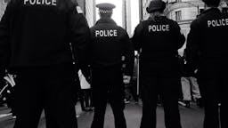 Police Rear View Of Police Force Standing On Street Against Buildings In City - stock photo