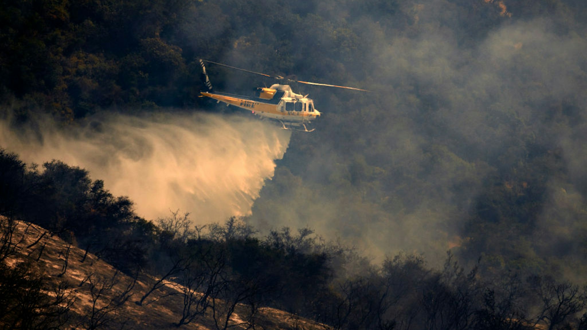 A helicopter makes a water drop on a wildfire in Mandeville Canyon in Los Angeles, California on May 28, 2017. More than 150 firefighters battle the fire that burns near multi-million dollar homes in the Brentwood neighborhood.