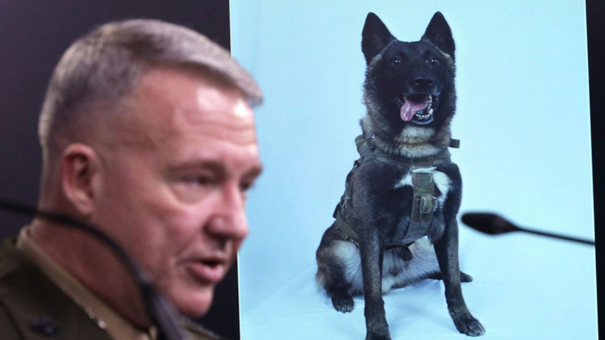 ARLINGTON, VIRGINIA - OCTOBER 30: U.S. Marine Corps Gen. Kenneth McKenzie, commander of U.S. Central Command, speaks as a picture of the canine that was part of the operation, is on display during a press briefing October 30, 2019 at the Pentagon in Arlington, Virginia. Gen. McKenzie and Hoffman spoke to the media to provide an update on the special operations raid that targeted former ISIS leader Abu Bakr al-Baghdadi in Idlib Province, Syria.