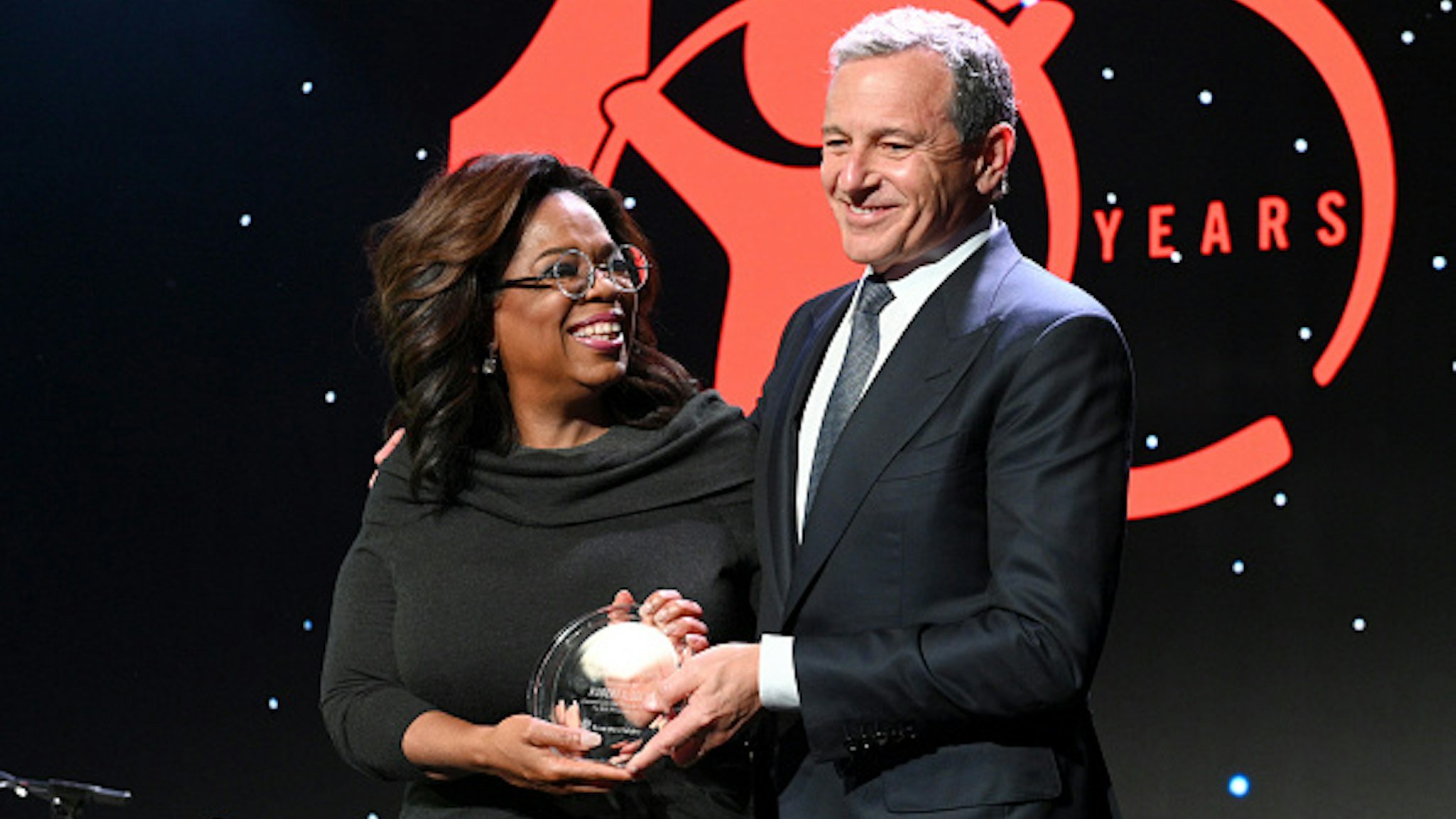 BEVERLY HILLS, CALIFORNIA - OCTOBER 02: Centennial Award Honoree, Robert A. Iger accepts the award from Oprah Winfrey onstage during the Save The Children's Centennial Celebration: Once in a Lifetime at The Beverly Hilton Hotel on October 02, 2019 in Beverly Hills, California.