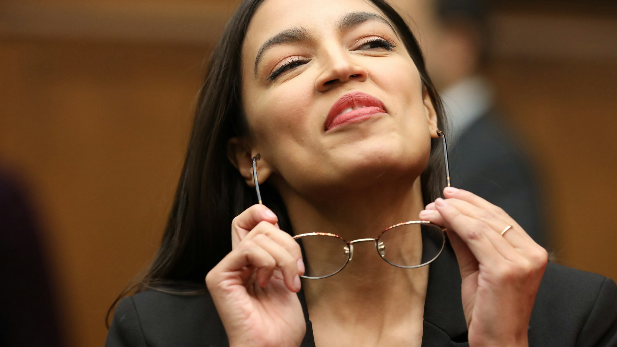 WASHINGTON, DC - OCTOBER 23: House Financial Services Committee member Rep. Alexandria Ocasio-Cortez (D-NY) puts on her glasses as the committee takes a break in the testimony of Facebook co-founder and CEO Mark Zuckerberg in the Rayburn House Office Building on Capitol Hill October 23, 2019 in Washington, DC. Zuckerberg testified about Facebook's proposed cryptocurrency Libra, how his company will handle false and misleading information by political leaders during the 2020 campaign and how it handles its users’ data and privacy.