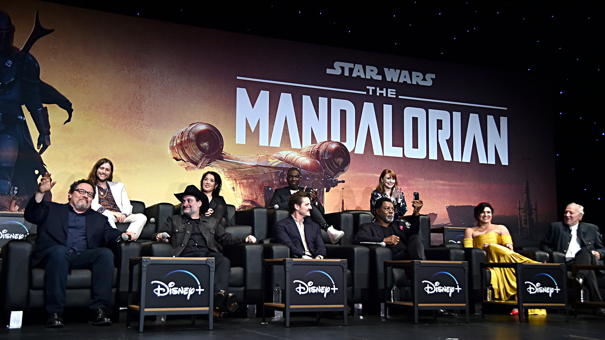 HOLLYWOOD, CALIFORNIA - NOVEMBER 13: (L-R) Executive Producer Jon Favreau, Composer Ludwig Göransson, Executive Producer/Director Dave Filoni, Director Deborah Chow, Pedro Pascal, Rick Famuyiwa, Carl Weathers, Director Bryce Dallas Howard, Gina Carano and Werner Herzog speak onstage at the premiere of Lucasfilm's first-ever, live-action series, "The Mandalorian," at the El Capitan Theatre in Hollywood, Calif. on November 13, 2019. "The Mandalorian" streams exclusively on Disney+. (Photo by Alberto E. Rodriguez/Getty Images for Disney)