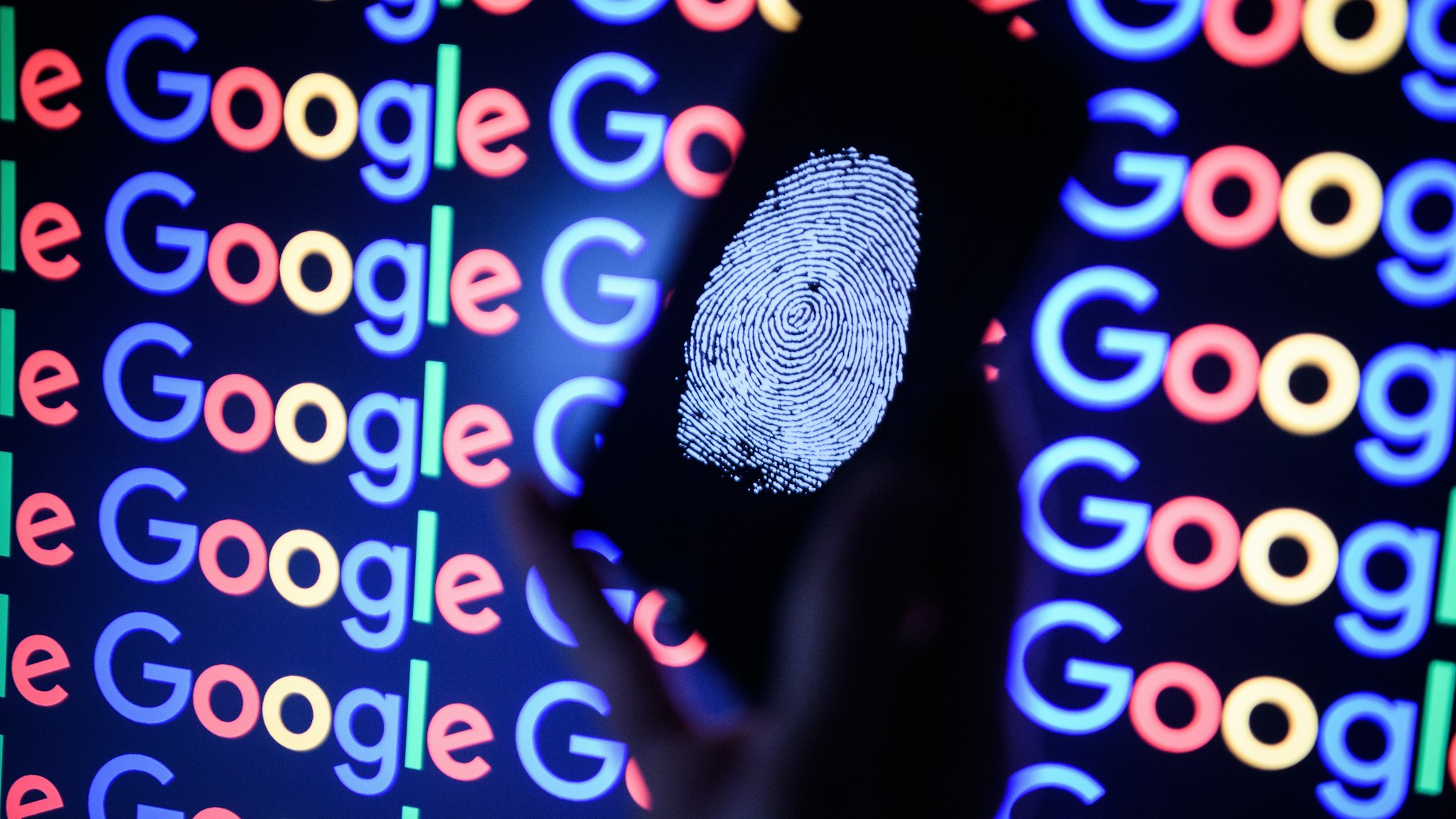 In this photo illustration, A thumbprint is displayed on a mobile phone while the Google logo is displayed on a computer monitor on August 09, 2017 in London, England. Founded in 1995 by Sergey Brin and Larry Page, Google now makes hundreds of products used by billions of people across the globe, from YouTube and Android to Smartbox and Google Search.