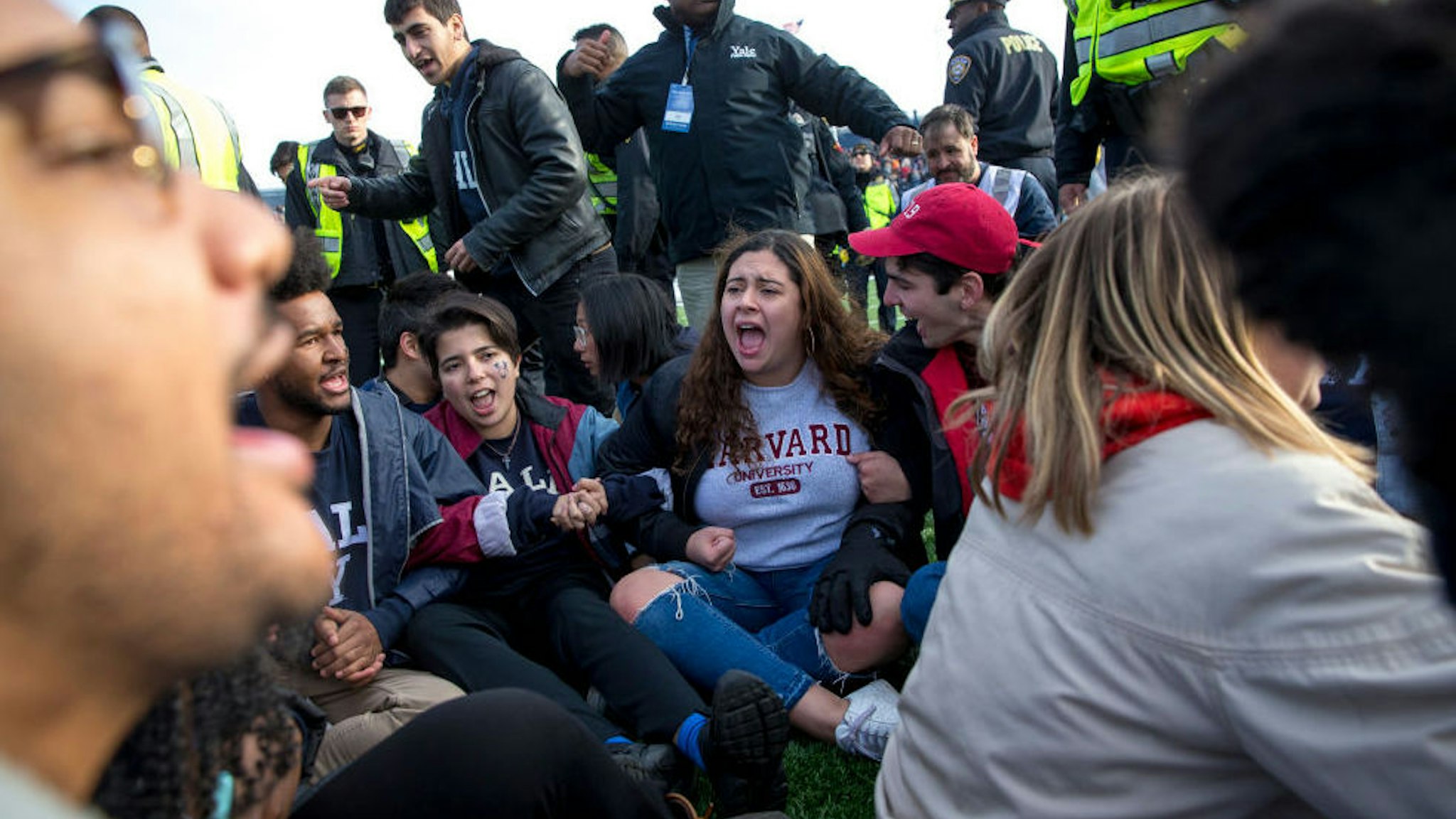 NEW HAVEN, CT - NOVEMBER 23: Harvard and Yale students protest during the halftime of the college football game between Harvard and Yale at the Yale Bowl in New Haven, CT on Saturday, Nov. 23, 2019. Demonstrators stormed the field during halftime at the Harvard-Yale football game Saturday, delaying the game for about an hour to demand that both universities divest their investments in fossil fuels and to call attention to the issue of climate change. The protest, which began with a few dozen protesters staging a sit-in midfield as the Yale band finished its halftime routine, swelled to about 500 people at one point as others in the stands joined the demonstration.