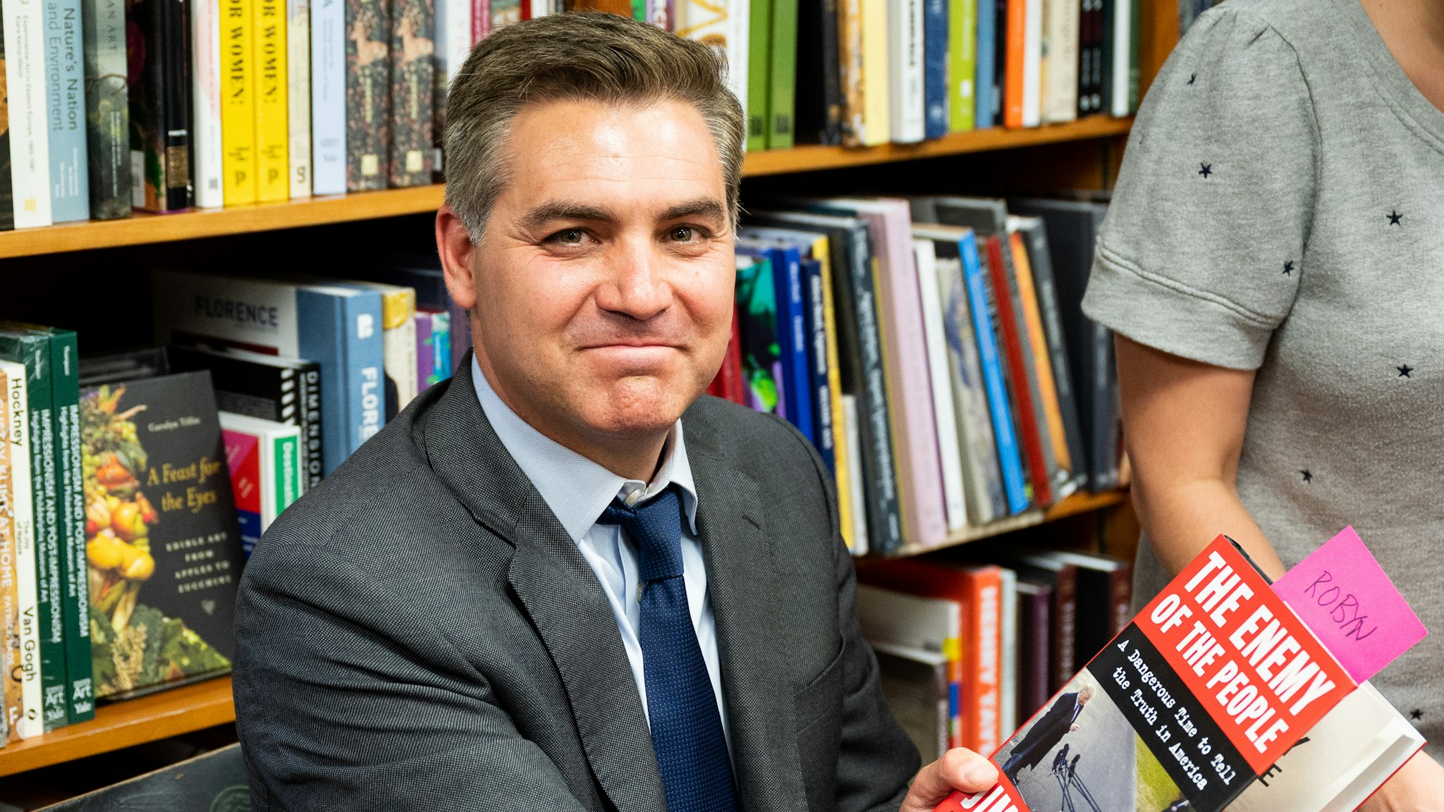 WASHINGTON, D C , UNITED STATES - 2019/06/18: Jim Acosta holds his book "The Enemy of the People: A Dangerous Time to Tell the Truth in America" at the Politics and Prose bookstore in Washington, DC.