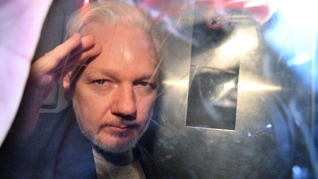 WikiLeaks founder Julian Assange gestures from the window of a prison van as he is driven out of Southwark Crown Court in London on May 1, 2019, after having been sentenced to 50 weeks in prison for breaching his bail conditions in 2012. - A British judge on Wednesday sentenced WikiLeaks founder Julian Assange to 50 weeks in prison for breaching his bail conditions in 2012. Assange took refuge in Ecuador's London embassy to avoid extradition to Sweden and was only arrested last month after Ecuador withdrew his asylum status. (Photo by Daniel LEAL-OLIVAS / AFP) (Photo credit should read DANIEL LEAL-OLIVAS/AFP via Getty Images)