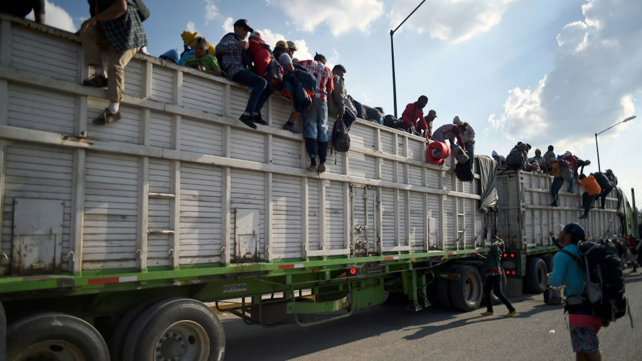 Central American migrants -mostly Hondurans- taking part in a caravan heading to the US, descend from a truck, on arrival at a temporary shelter in Irapuato, Guanajuato state, Mexico on November 11, 2018. - The trek from tropical Central America to the huge capital of Mexico is declining the health of the migrant caravan that endures extreme climate changes, as well as overcrowding and physical exhaustion, and still has to face the desert that leads to the United States. (Photo by ALFREDO ESTRELLA / AFP) (Photo credit should read ALFREDO ESTRELLA/AFP via Getty Images)