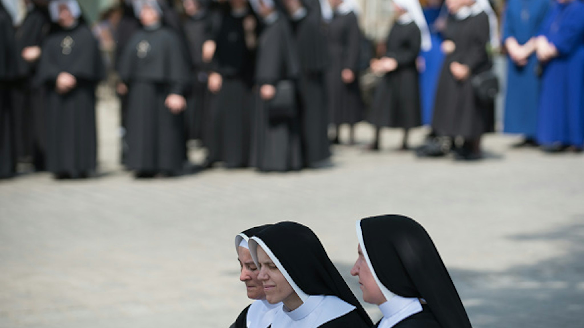 KRAKOW, POLAND - 2018/05/31: Three nuns take a rest under a tree during the Corpus Christi procession in Krakow. The Feast of Corpus Christi or Body of Christ, is the Roman Rite liturgical solemnity celebrating the real presence of the body and blood of Jesus Christ, the Son of God, in the Eucharist . Corpus Christi takes place 60 days after Easter, and every year the procession starts at Wael Castle and ends at the Main Square.
