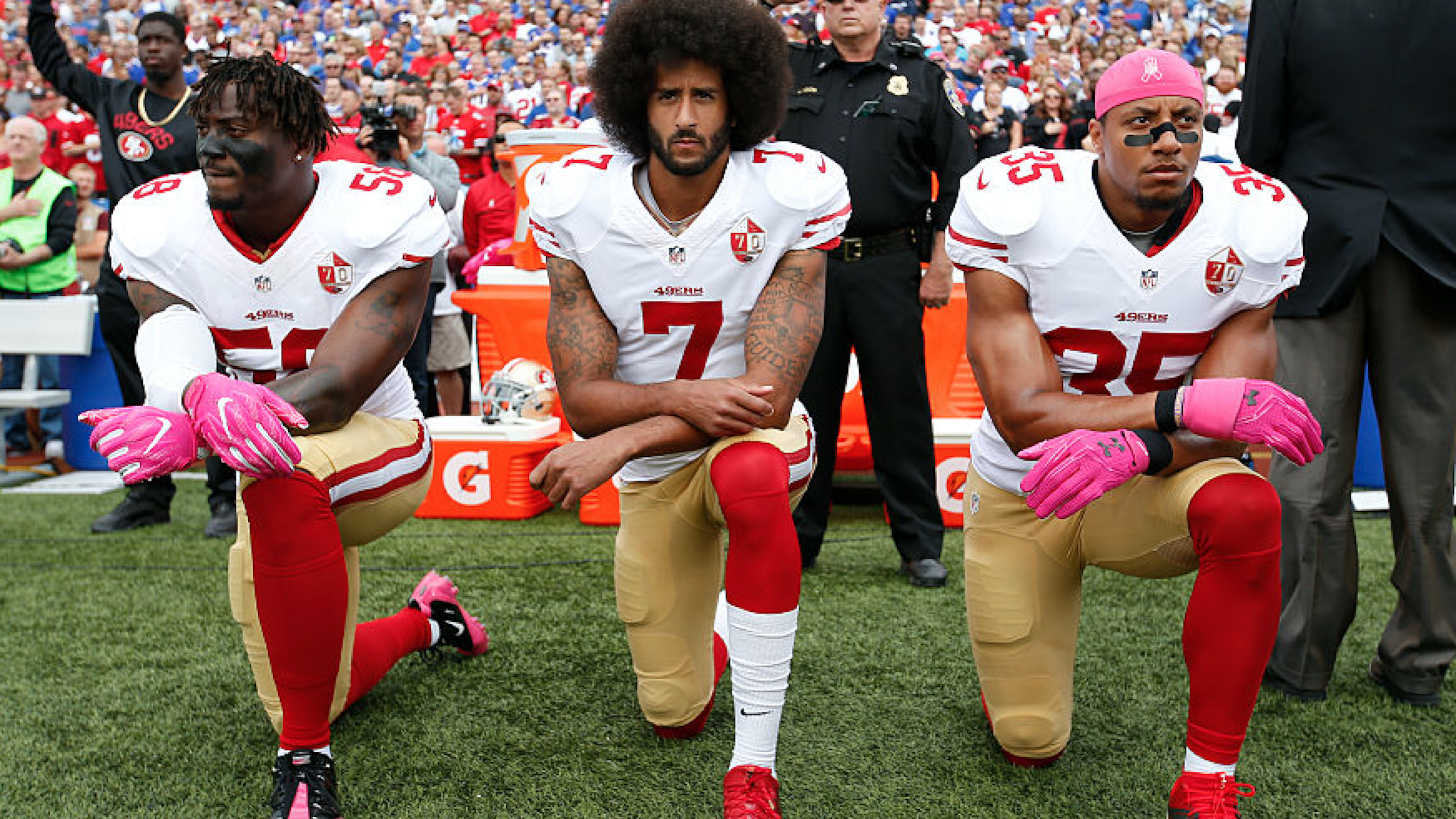 Eli Harold #58, Colin Kaepernick #7 and Eric Reid #35 of the San Francisco 49ers kneel in protest on the sideline, during the anthem, prior to the game against the Buffalo Bills at New Era Field on October 16, 2016 in Orchard Park, New York.