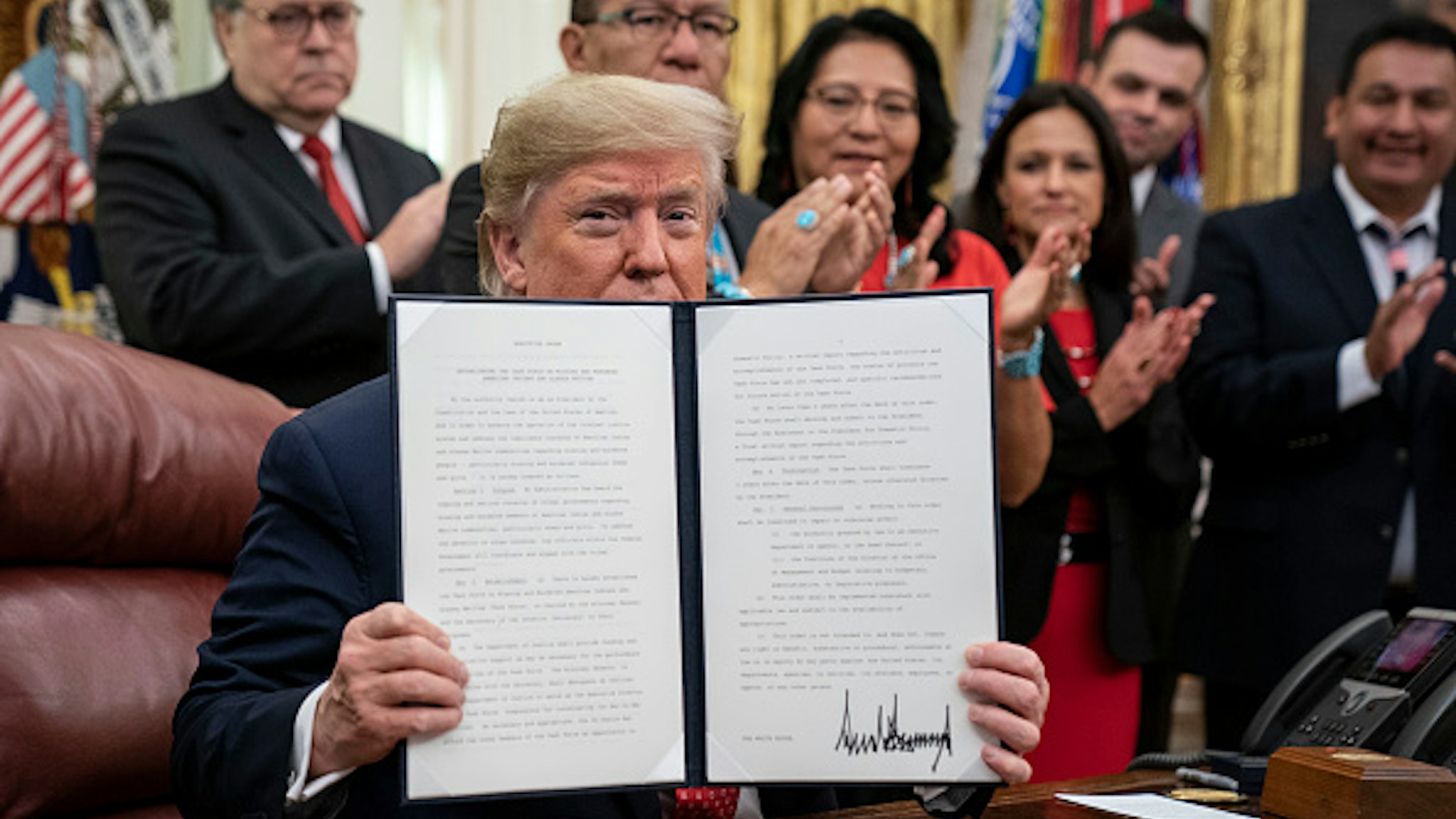 WASHINGTON, DC - NOVEMBER 26: U.S. President Donald Trump displays a signed copy of an executive order establishing the Task Force on Missing and Murdered American Indians and Alaska Natives, in the Oval Office of the White House on November 26, 2019 in Washington, DC. Attorney General William Barr recently announced the initiative on a trip to Montana where he met with Confederated Salish Kootenai Tribe leaders.
