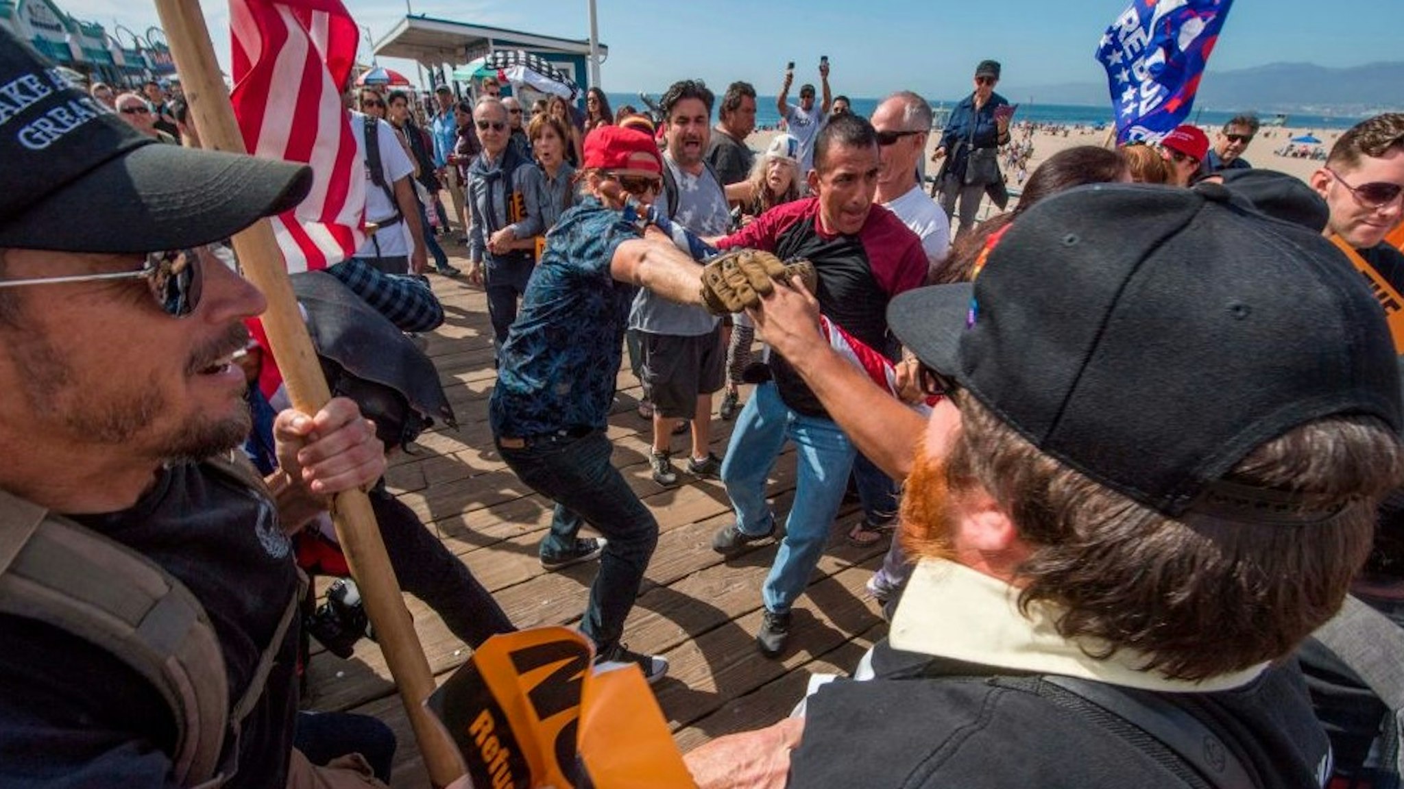 Supporters of President Donald Trump (L) clash with anti-Trump protesters during a rally against his policies in Santa Monica, California on October 19, 2019. - Several people were arrested after fighting and pepper spray was used by the opposing groups.