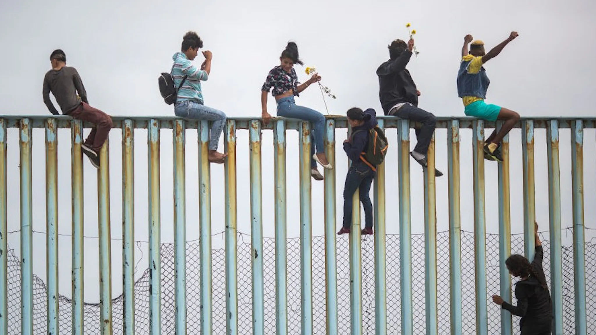 Migrants In Caravan That Travelled Through Mexico Attempt To Be Granted Asylum At U.S. Border People climb a section of border fence to look toward supporters in the U.S. as members of a caravan of Central American )