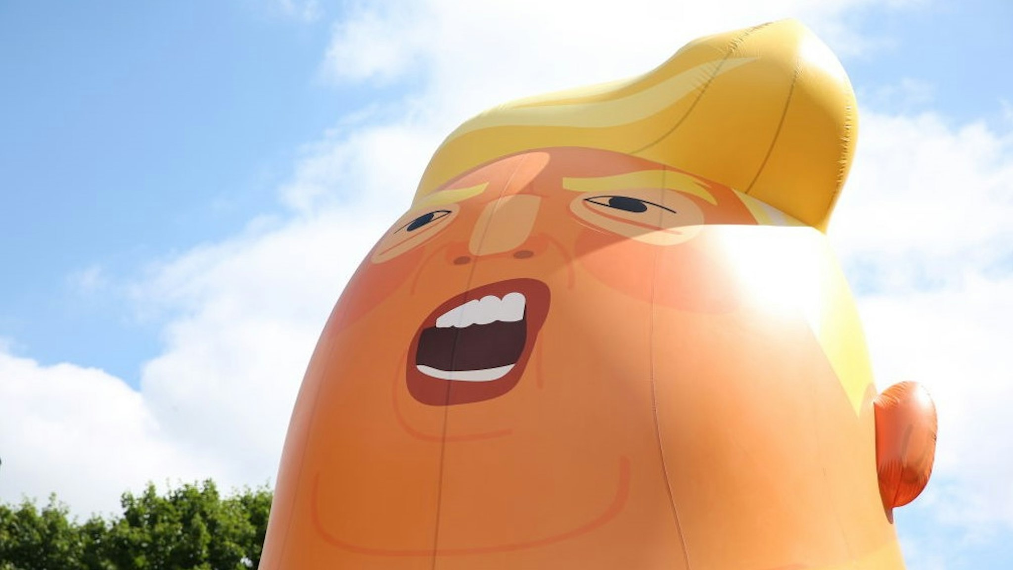 Activists inflate a giant balloon depicting US President Donald Trump as an orange baby in north London on July 10, 2018 ahead of a demonstration in London to coincide with the visit of the US president. - A barrage of nationwide protests will greet US President Donald Trump's four-day trip to Britain from Thursday, with organisers hoping to stage one of the country's biggest demonstrations in decades following a series of diplomatic spats. A giant inflatable "Baby Trump" balloon will be flown near the Houses of Parliament ahead of the protest. (Photo by Isabel INFANTES / AFP) (Photo credit should read