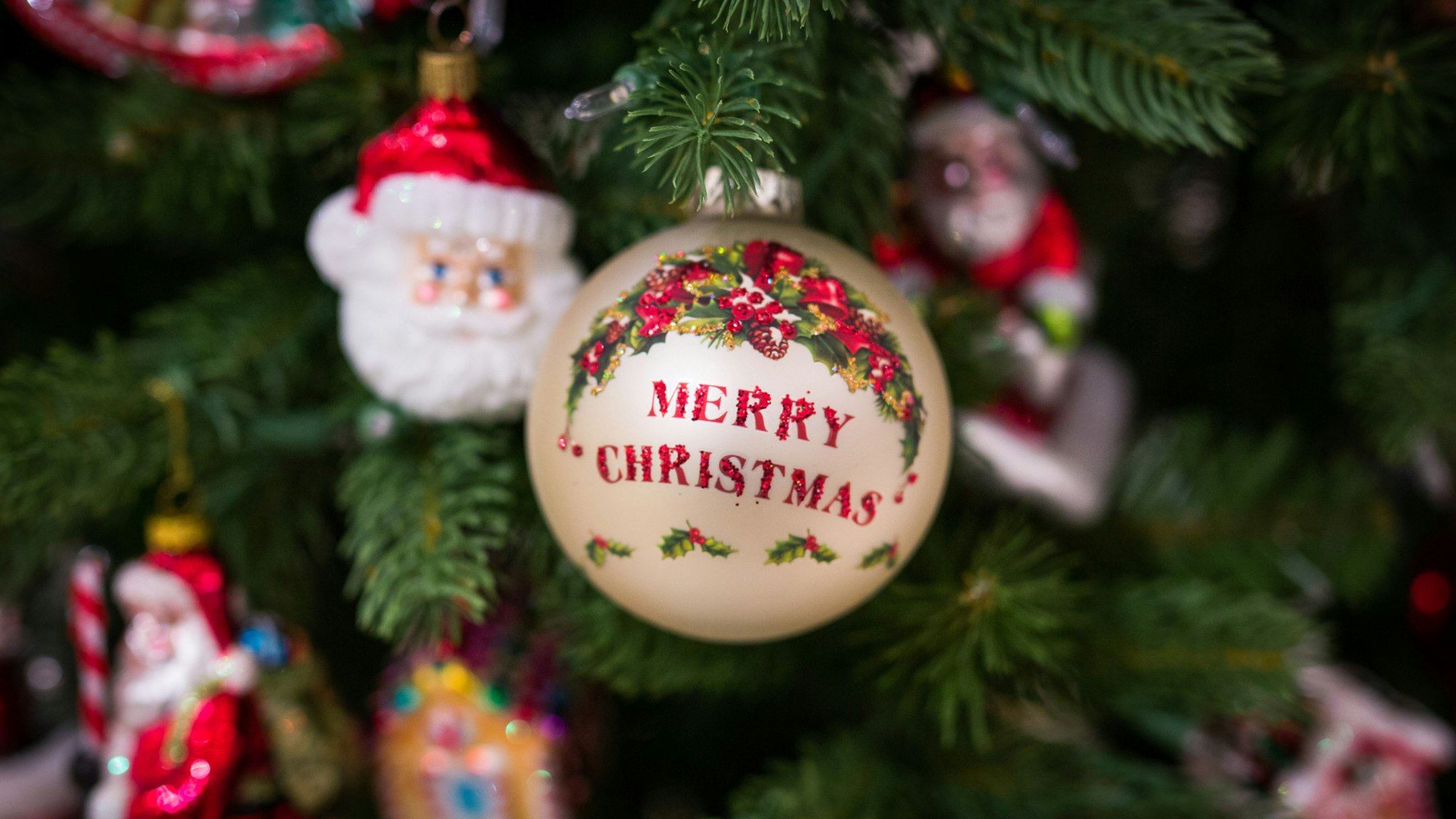 A bauble emblazoned with Merry Christmas hangs from a Christmas tree on display during the opening day of the Christmas Shop in the Selfridges Plc department store in London, U.K., on Monday, Aug. 1, 2016.