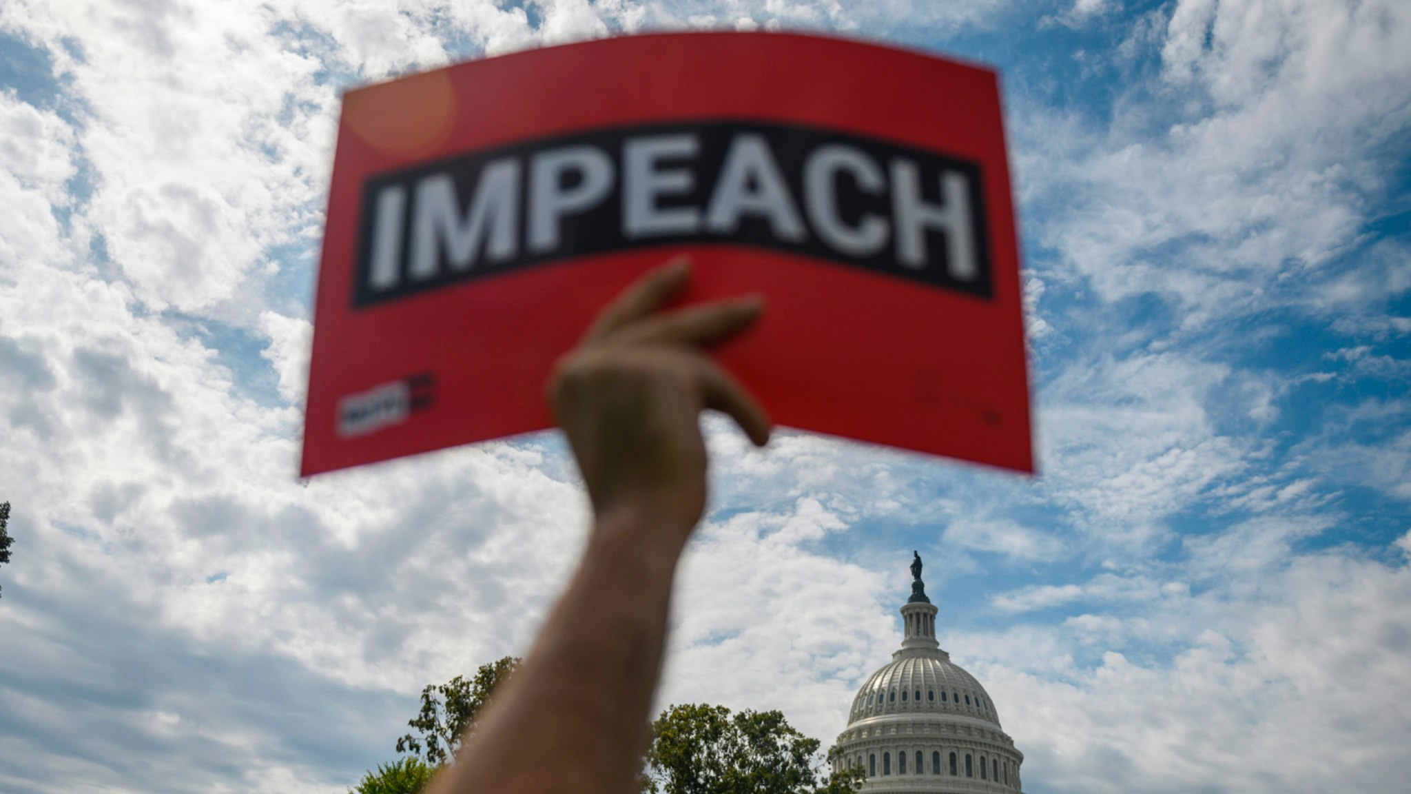 A protester holds up a sign reading "impeach" outside the US Capitol building during the "People's Rally for Impeachment" on Capitol Hill in Washington, DC on September 26, 2019.